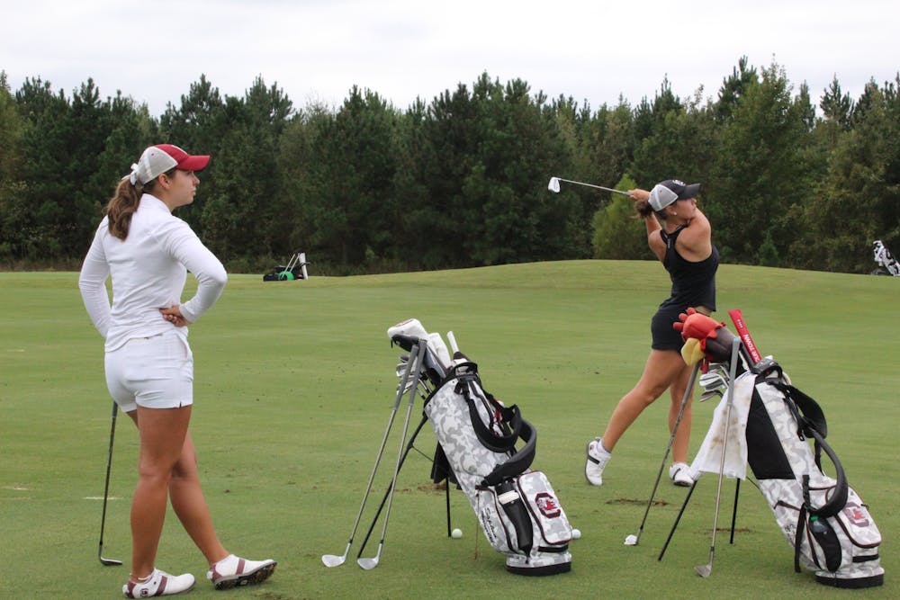 <p>Sophomore Camila Burnett hits a drive while her sister, senior Sophia Burnett, watches on Sept. 28, 2023. The duo said they have enjoyed their sibling rivalry and camaraderie since Camila joined the team in spring 2023.</p>