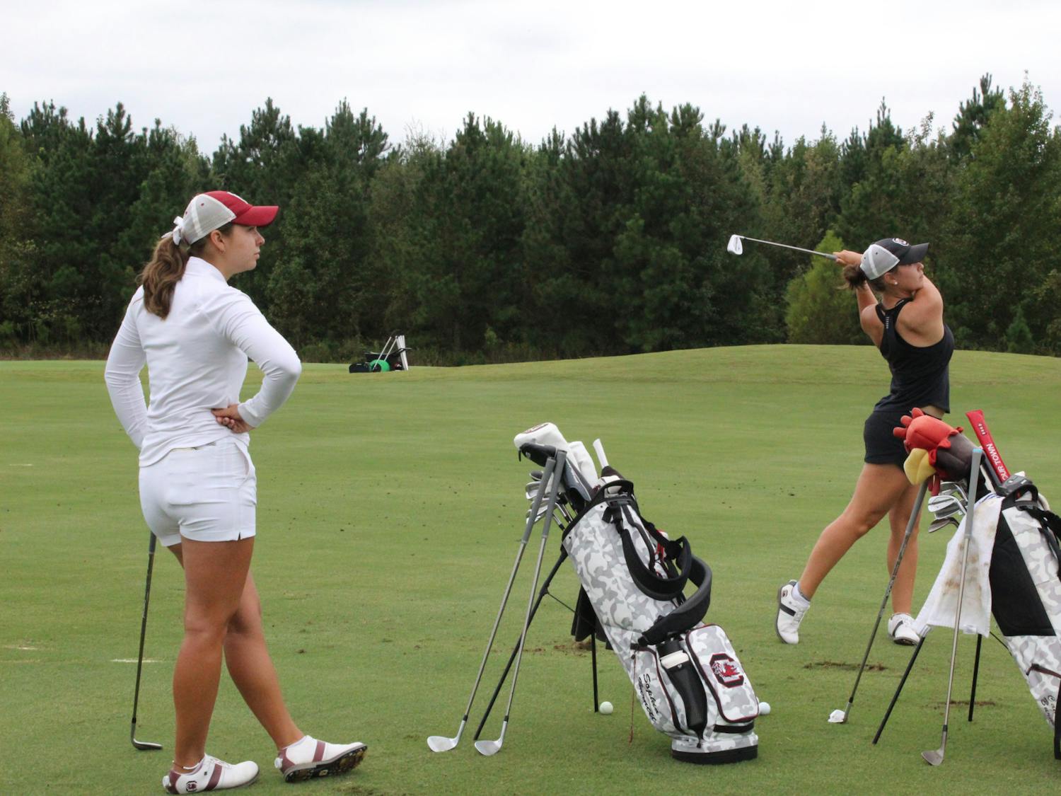 Sophomore Camila Burnett hits a drive while her sister, senior Sophia Burnett, watches on Sept. 28, 2023. The duo said they have enjoyed their sibling rivalry and camaraderie since Camila joined the team in spring 2023.