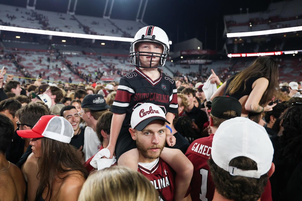 <p>FILE – A young South Carolina fan sits on a man's shoulders in a crowd of people on the field at Williams-Brice Stadium on Nov. 2, 2024. South Carolina students and fans rushed the field after the team defeated then-No. 10 Texas A&amp;M for the school's homecoming game.</p>