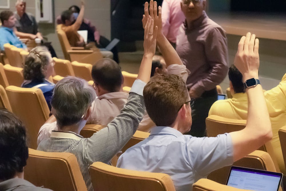 <p>American Association of University Professors (AAUP) president Carol Harrison (left) and vice president Mark Minett (right) raise their hands to vote on a proposed amendment during the faculty senate meeting on April 19, 2023, in the Booker T. Washington Auditorium. Harrison spoke on the necessity for universities to prioritize the values they hold students and faculty to.</p>
