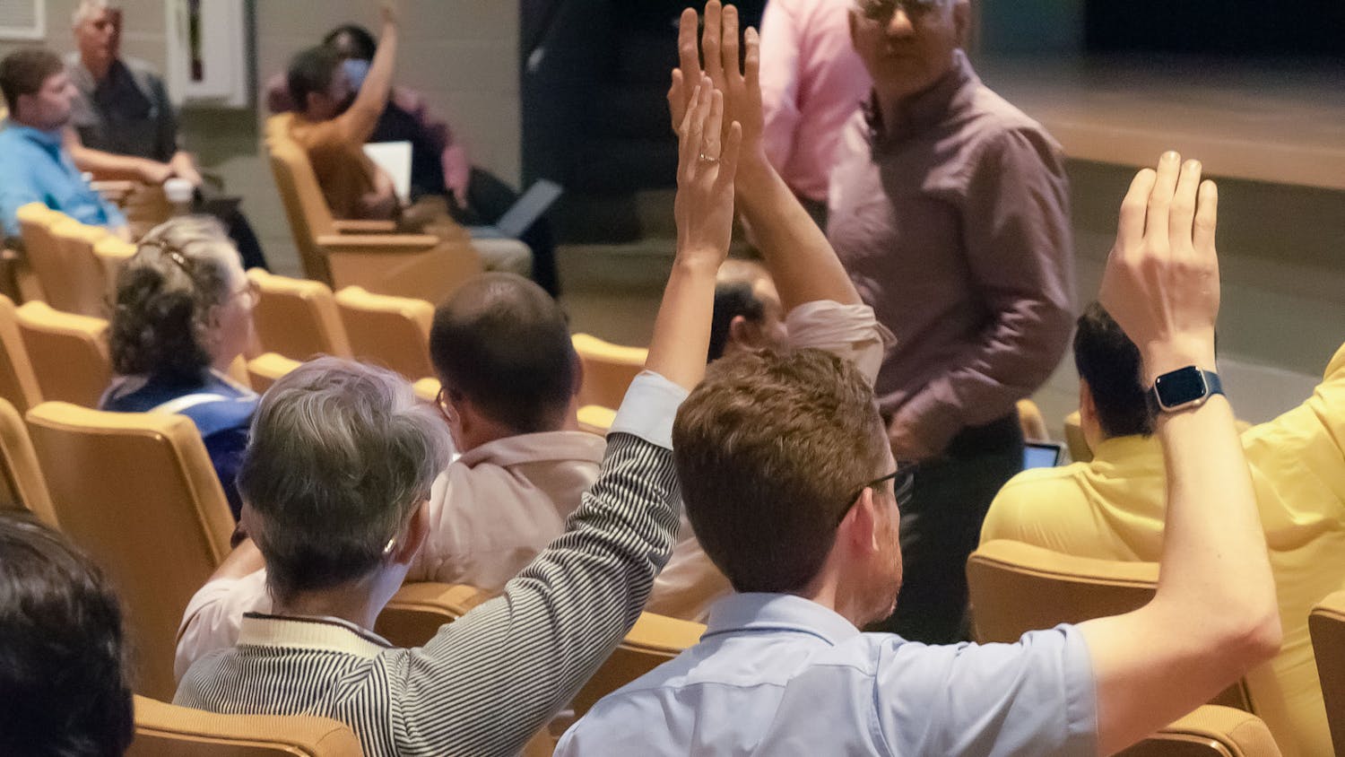 American Association of University Professors (AAUP) president Carol Harrison (left) and vice president Mark Minett (right) raise their hands to vote on a proposed amendment during the faculty senate meeting on April 19, 2023, in the Booker T. Washington Auditorium. Harrison spoke on the necessity for universities to prioritize the values they hold students and faculty to.