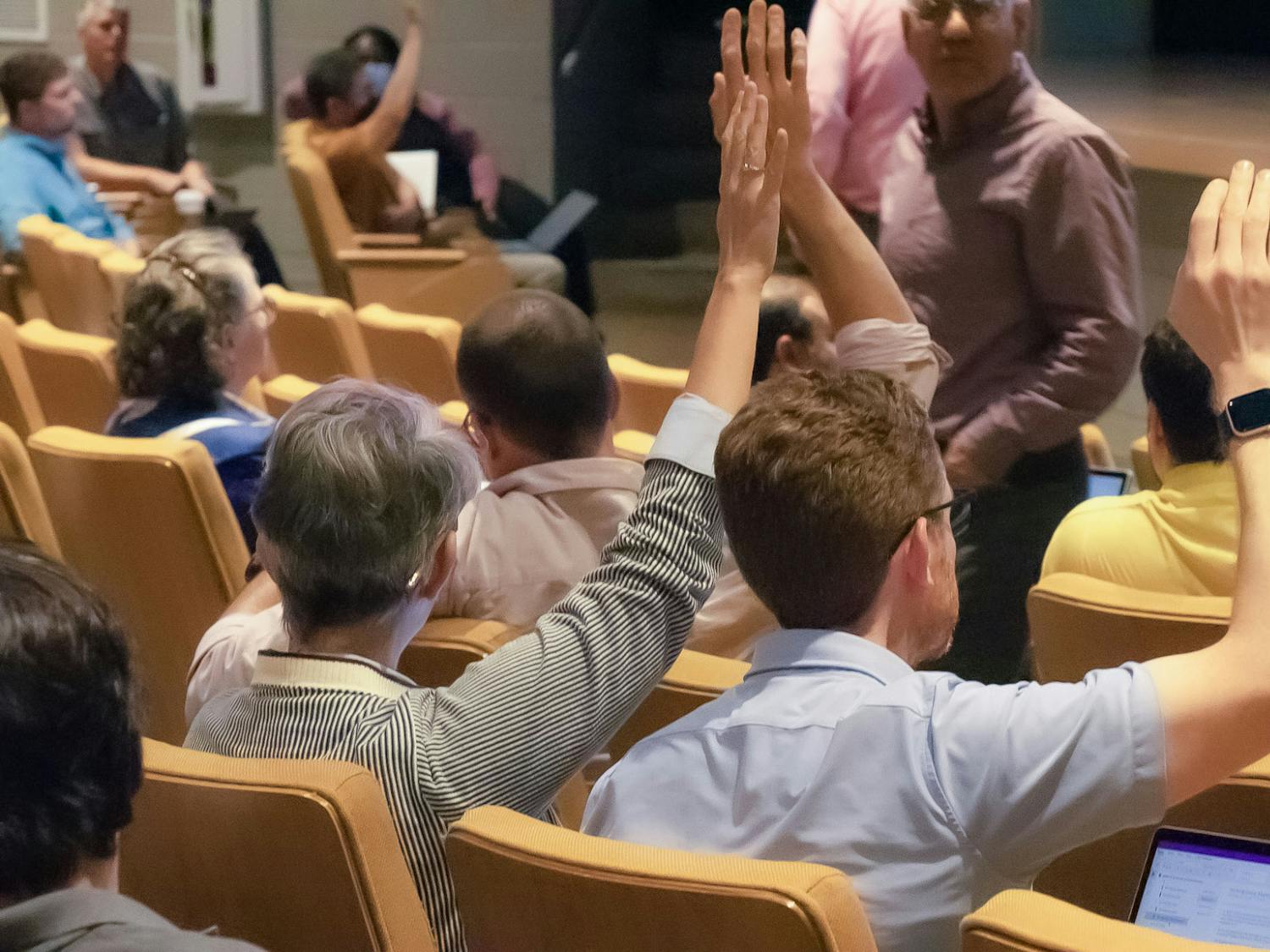 American Association of University Professors (AAUP) president Carol Harrison (left) and vice president Mark Minett (right) raise their hands to vote on a proposed amendment during the faculty senate meeting on April 19, 2023, in the Booker T. Washington Auditorium. Harrison spoke on the necessity for universities to prioritize the values they hold students and faculty to.