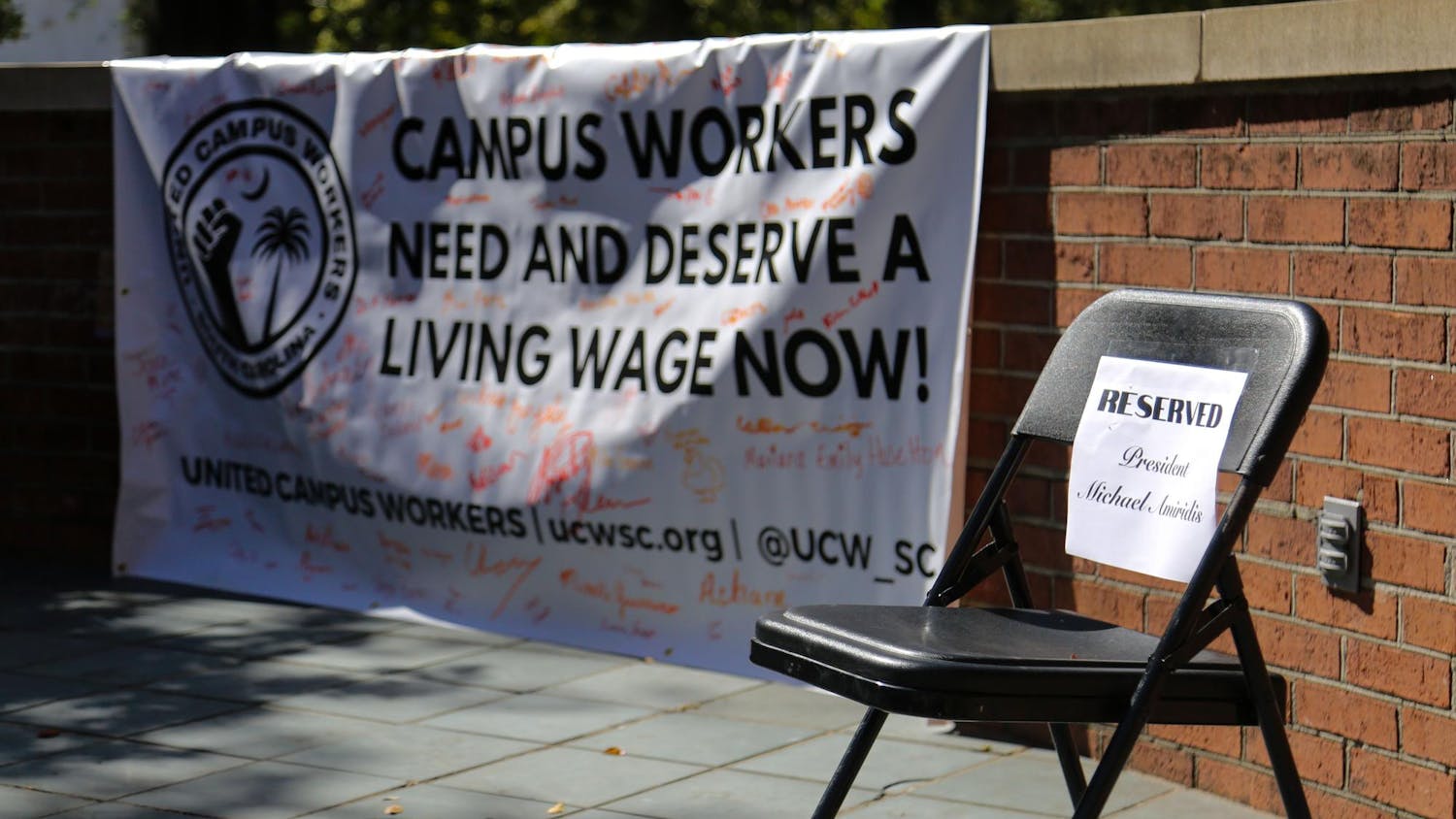 FILE — A folding chair reserved for University of South Carolina President Michael Amiridis sits empty on the stage of the Russell House patio during a USC worker speak-out event on Oct. 26, 2023. The event was hosted by the United Campus Workers union at USC.