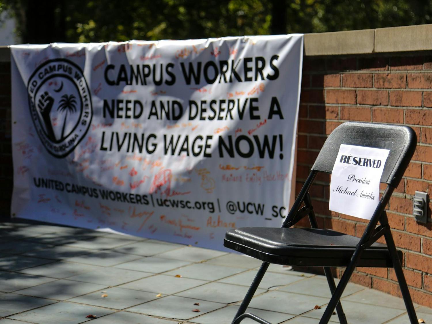 FILE — A folding chair reserved for University of South Carolina President Michael Amiridis sits empty on the stage of the Russell House patio during a USC worker speak-out event on Oct. 26, 2023. The event was hosted by the United Campus Workers union at USC.