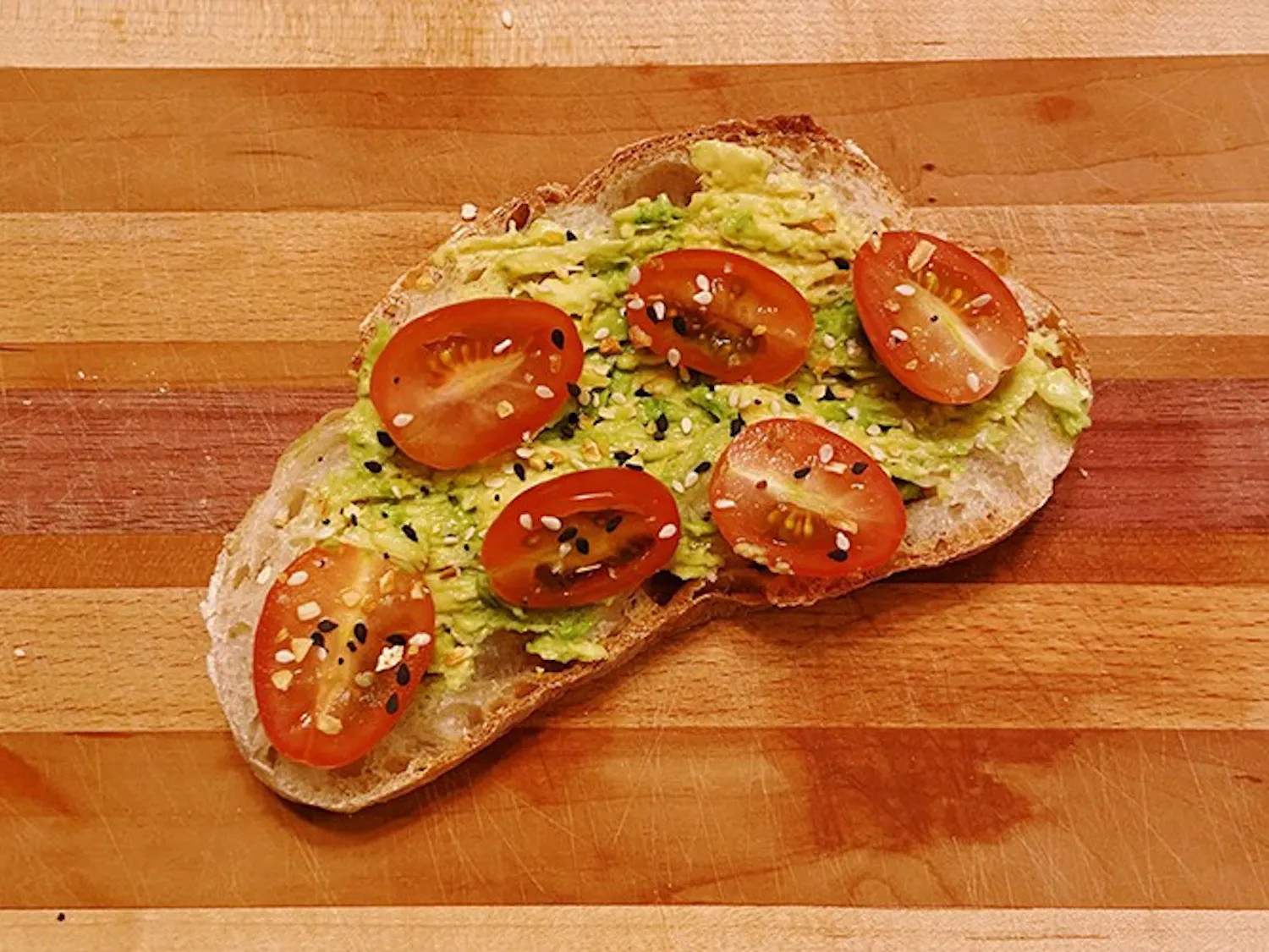  A piece of toast topped with avocado and tomato. 