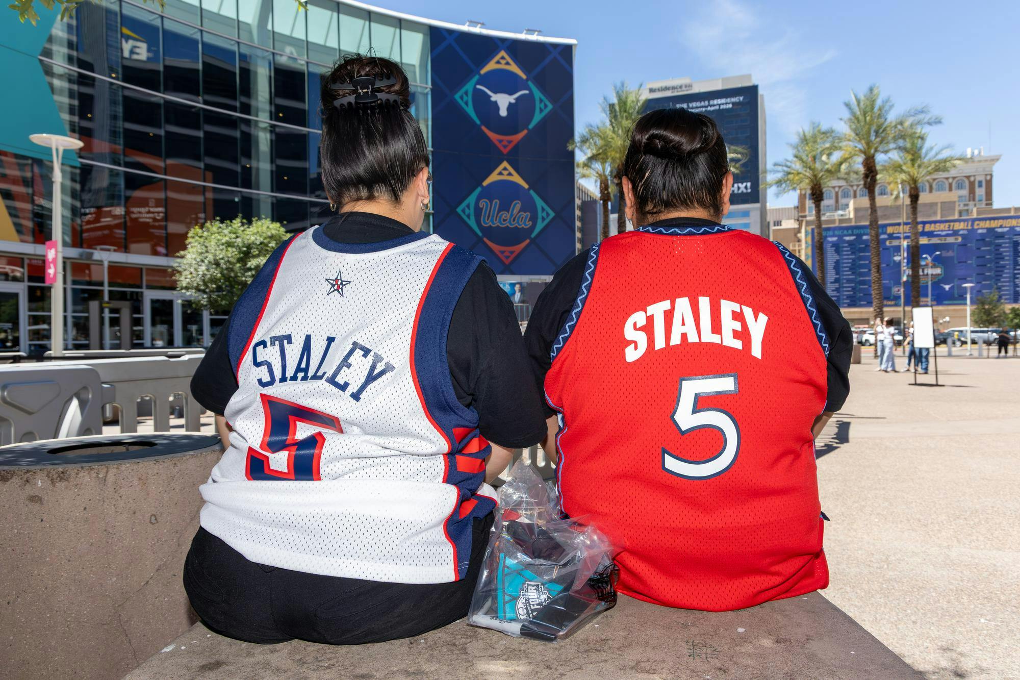 San Carlos, California, residents Kayla Kitcheyan and Jennifer Gutierrez sit outside the Mortgage Matchup Center in Phoenix, Arizona, while wearing Dawn Staley jerseys before the Final Four on April 3, 2026. The two came out to see Staley since it is the closest she has come to where the two live.