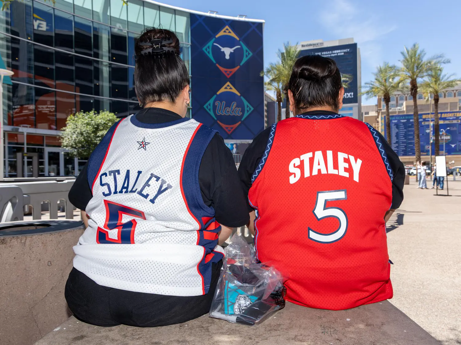 San Carlos, California, residents Kayla Kitcheyan and Jennifer Gutierrez sit outside the Mortgage Matchup Center in Phoenix, Arizona, while wearing Dawn Staley jerseys before the Final Four on April 3, 2026. The two came out to see Staley since it is the closest she has come to where the two live.