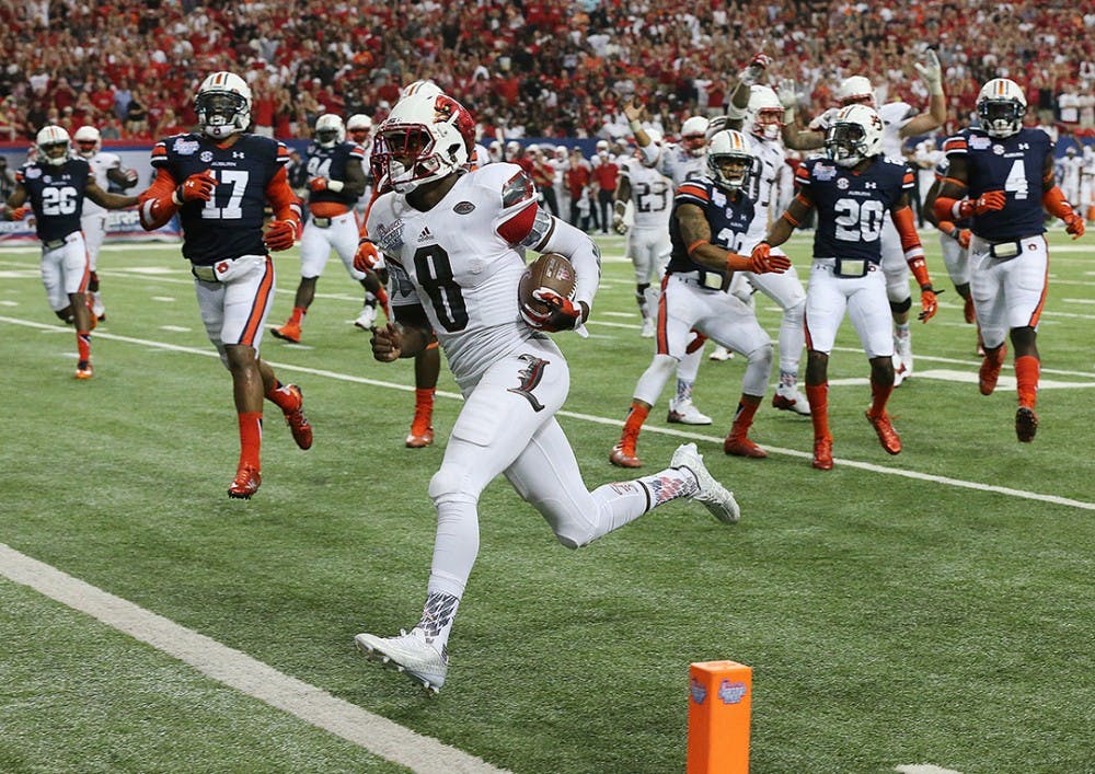 Louisville quarterback Lamar Jackson runs for a touchdown against Auburn defenders to cut the Auburn lead to 24-10 during the third quarter in the Chick-fil-A Kickoff Game on Saturday, Sept. 5, 2015, in Atlanta. Auburn won 31-24. (Curtis Compton/Atlanta Journal-Constitution/TNS) 