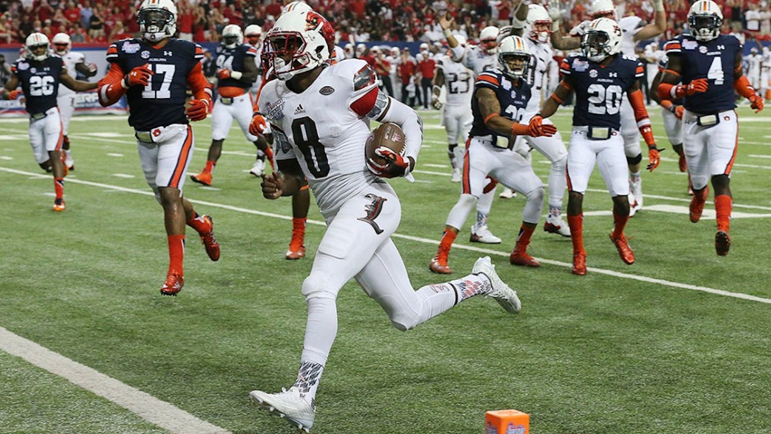 Louisville quarterback Lamar Jackson runs for a touchdown against Auburn defenders to cut the Auburn lead to 24-10 during the third quarter in the Chick-fil-A Kickoff Game on Saturday, Sept. 5, 2015, in Atlanta. Auburn won 31-24. (Curtis Compton/Atlanta Journal-Constitution/TNS) 