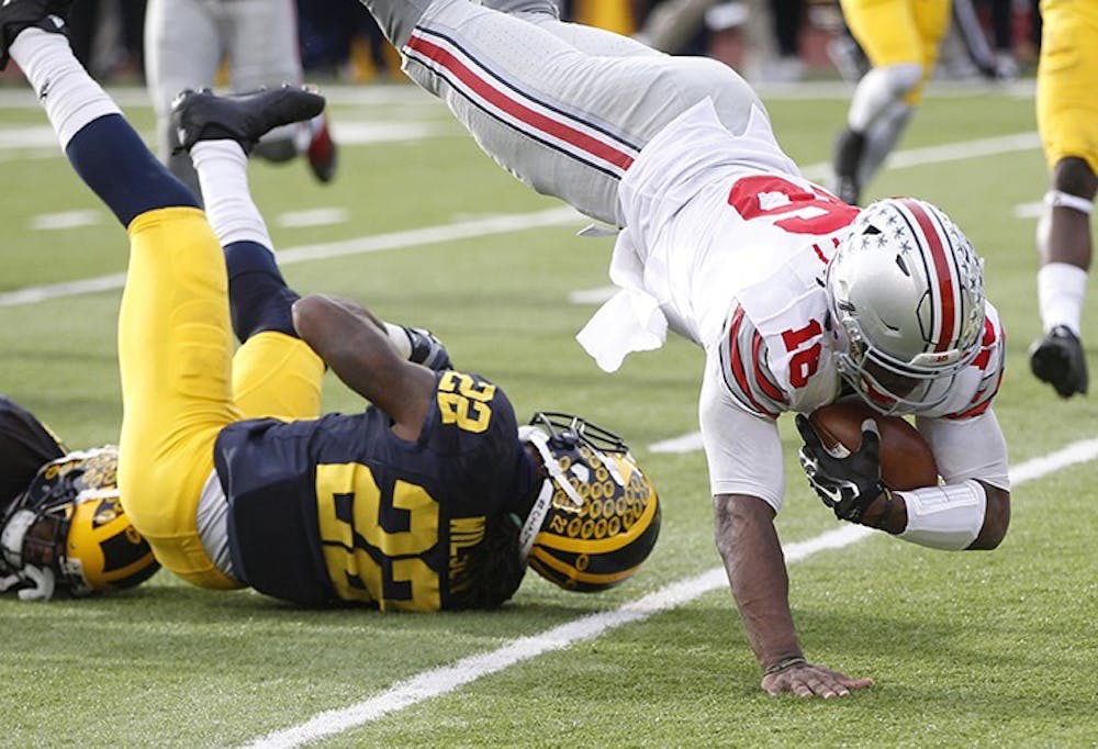 Ohio State quarterback J.T. Barrett, right, leaps over Michigan&apos;s Jarrod Wilson and into the end zone for a third-quarter touchdown on Saturday, Nov. 28, 2015, at Michigan Stadium in Ann Arbor, Mich. Ohio State won, 42-13. (Julian H. Gonzalez/Detroit Free Press/TNS)