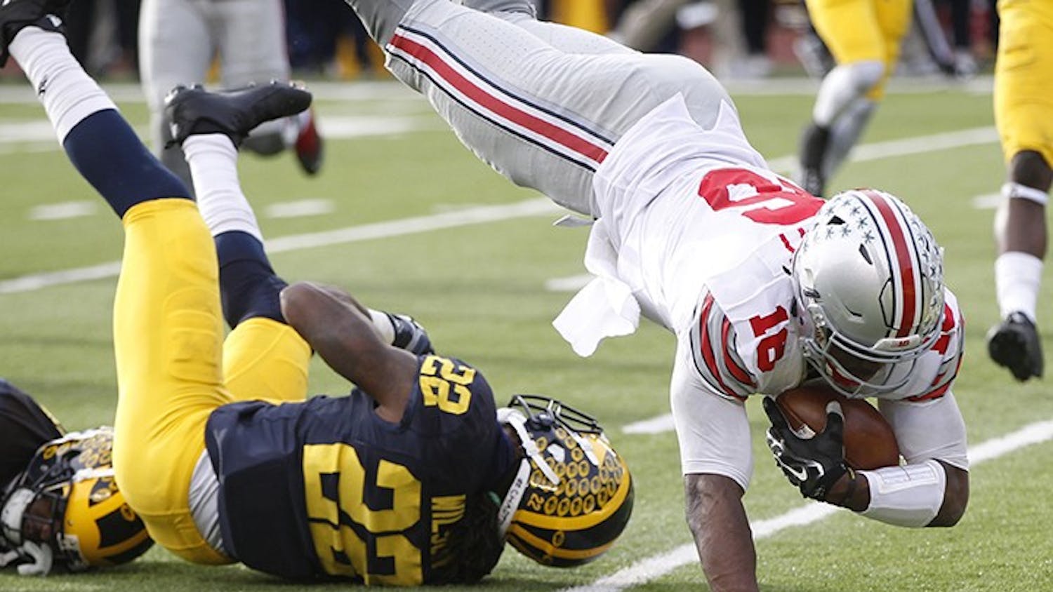 Ohio State quarterback J.T. Barrett, right, leaps over Michigan's Jarrod Wilson and into the end zone for a third-quarter touchdown on Saturday, Nov. 28, 2015, at Michigan Stadium in Ann Arbor, Mich. Ohio State won, 42-13. (Julian H. Gonzalez/Detroit Free Press/TNS)