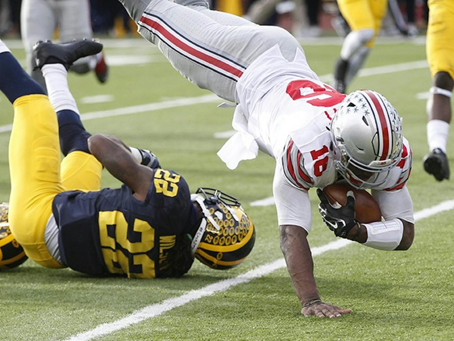 Ohio State quarterback J.T. Barrett, right, leaps over Michigan's Jarrod Wilson and into the end zone for a third-quarter touchdown on Saturday, Nov. 28, 2015, at Michigan Stadium in Ann Arbor, Mich. Ohio State won, 42-13. (Julian H. Gonzalez/Detroit Free Press/TNS)