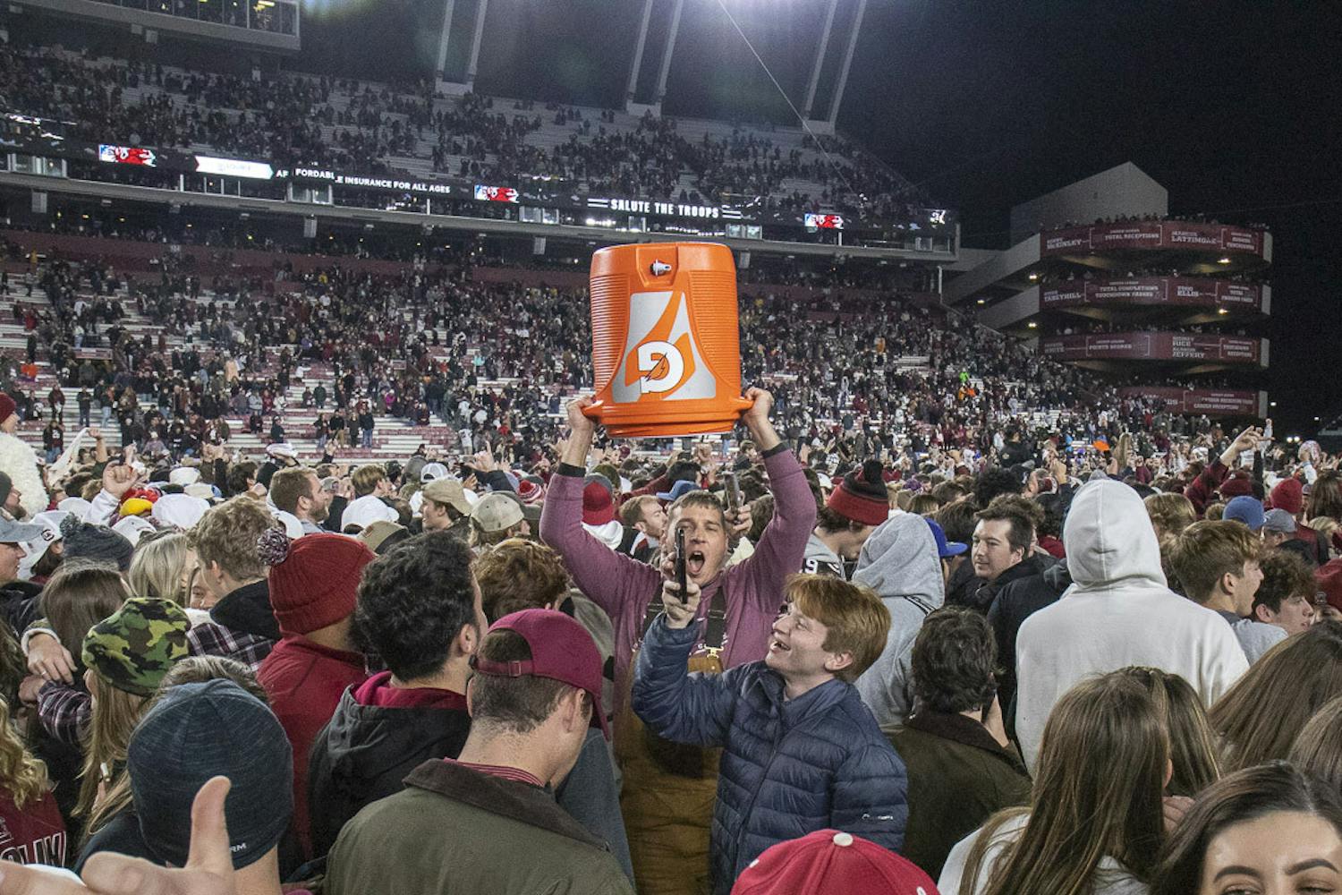 FILE—A South Carolina fan raises the Gatorade jug used to douse Gamecock head football coach Shane Beamer into the air after the 63-38 upset against Tennessee at Williams-Brice Stadium on Nov. 19, 2023. Gamecock students and fans rushed the field en masse after the unanticipated win over the Volunteers.
