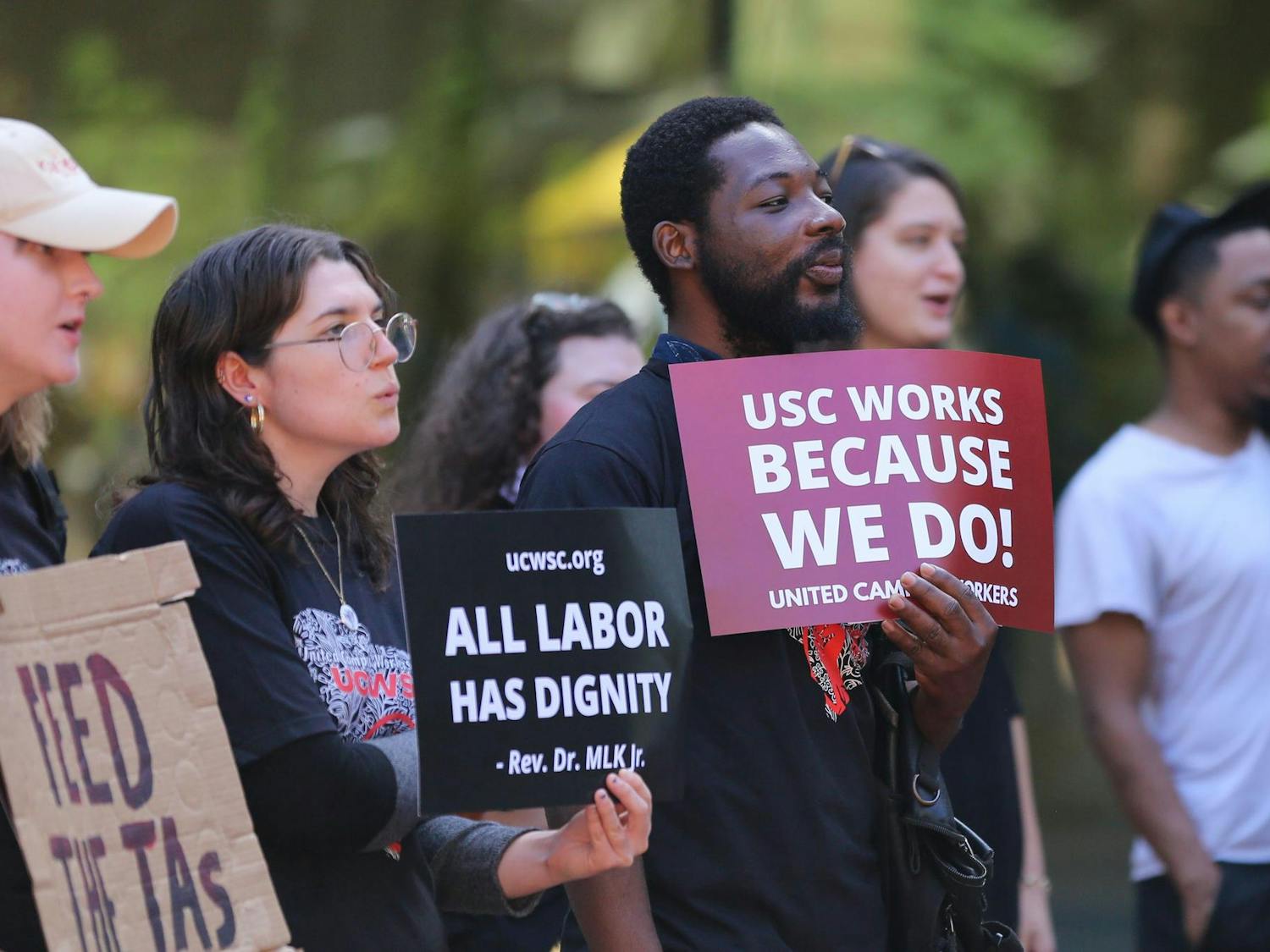USC students and employees hold signs with messages of support during a USC United Campus Workers speak-out event held on the Russell House patio on Oct. 26, 2023. The union has been pushing for an increase in wages for more than two years.