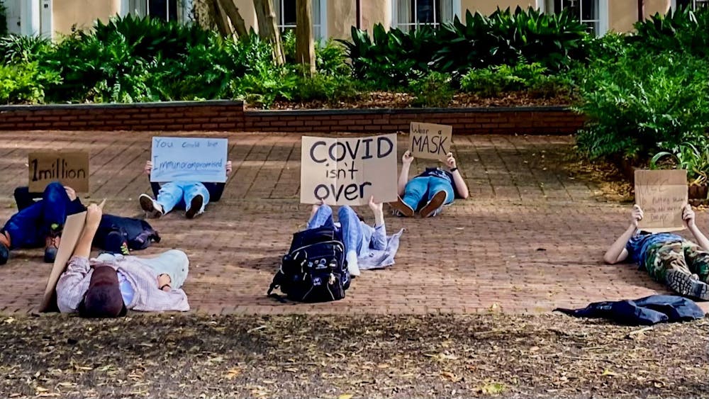 <p>Student protesters hold a "die down" demonstration, laying down in silence to honor those who have lost their life to COVID, during pro-mask protest on March 31, 2022. Pro-mask protesters gathered in the horseshoe to protest the removal of the school's mask mandate.</p>