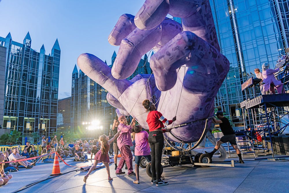 Musicians from the band Squonk and audience members work together to manipulate the purple hands during the band's 'Hand to Hand' performance on their 2019 tour.