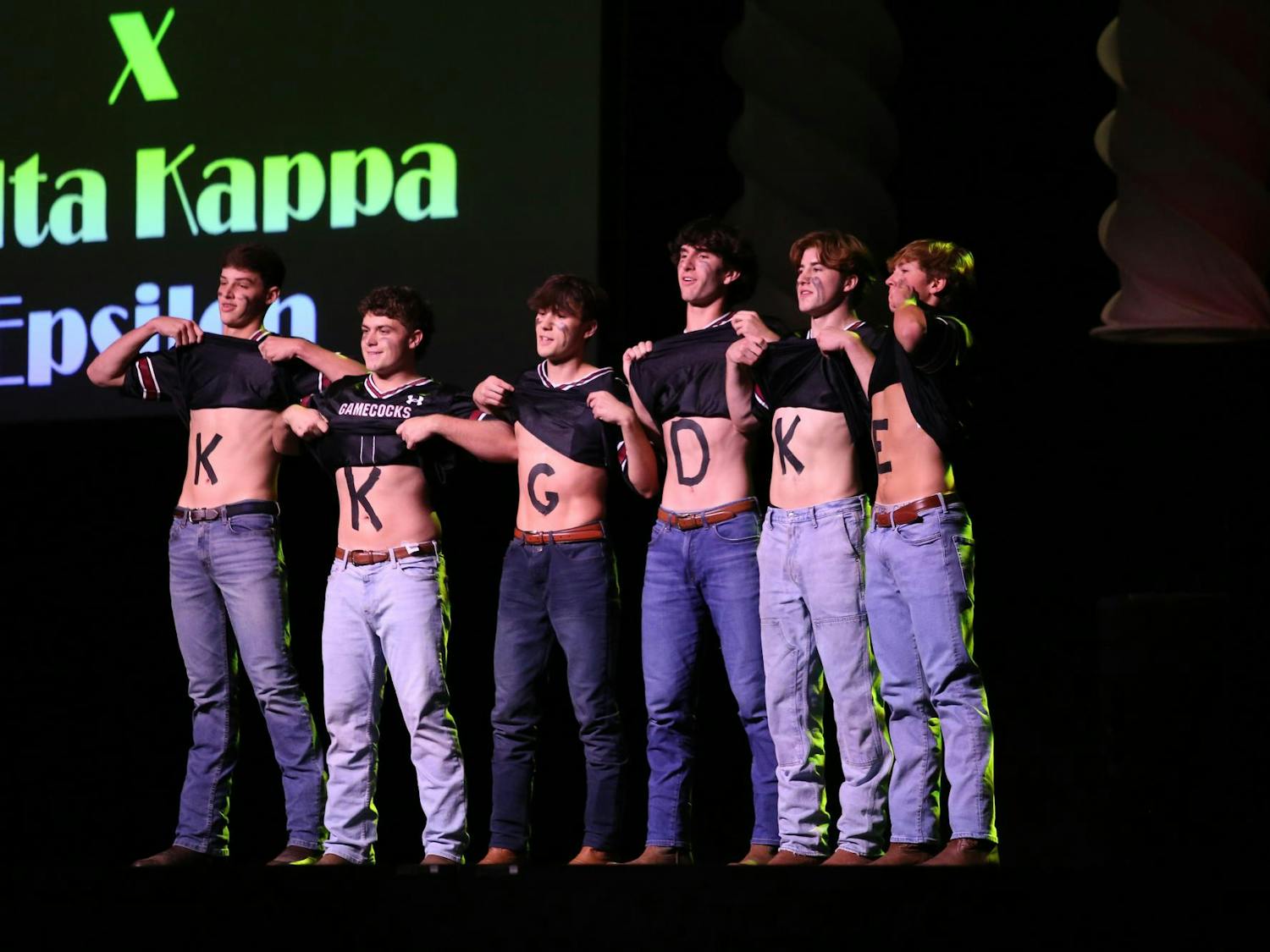 Brothers of Delta Kappa Epsilon perform at Spurs and Struts with the letters of Kappa Kappa Gamma spelled out on their chests under football jerseys. Delta Kappa Epsilon partnered with Kappa Kappa Gamma for its performance in Spurs and Struts.