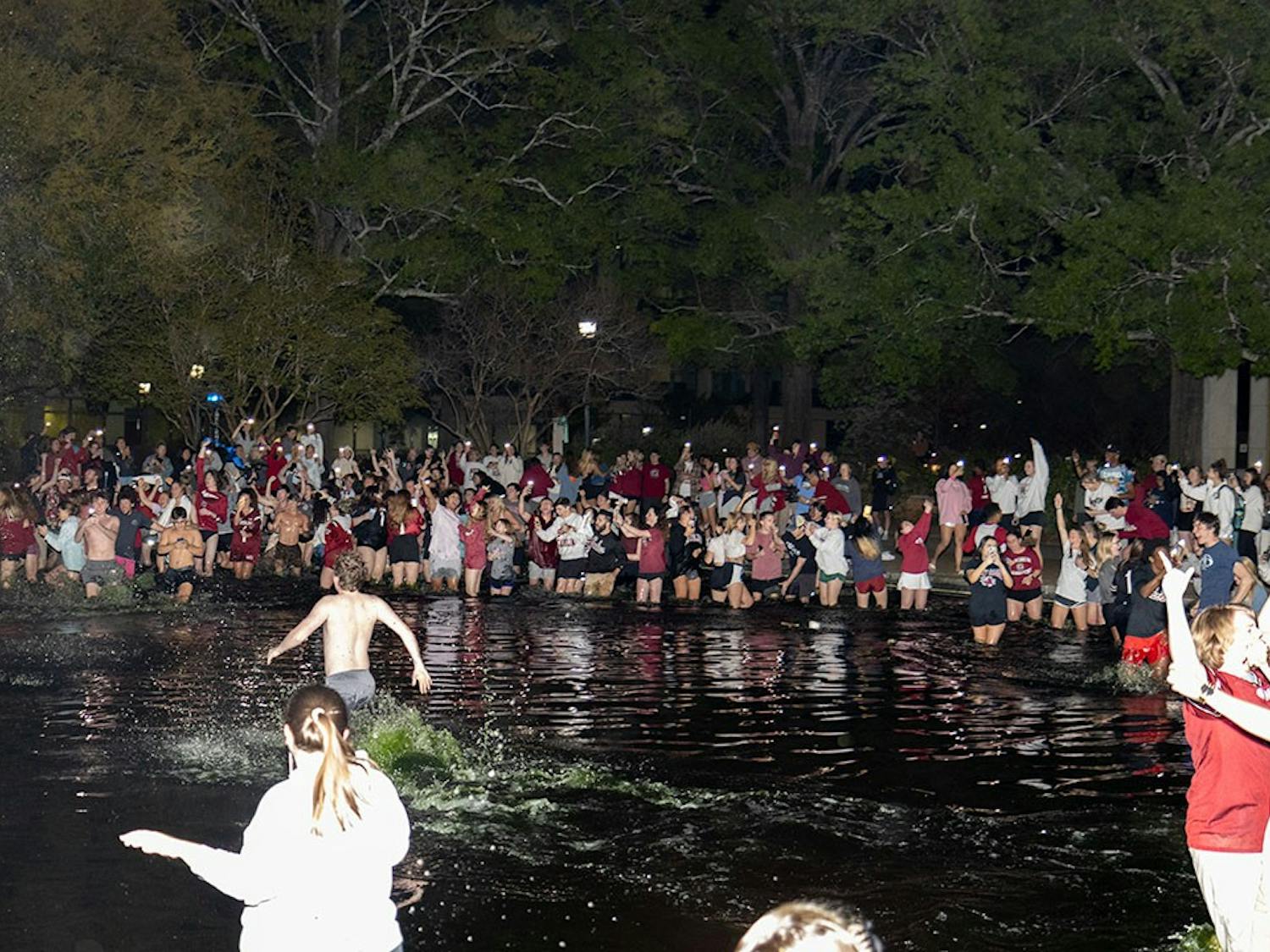 As the buzzer sounds marking the end of the fourth quarter of the NCAA National Championships, Gamecock fans pour into the reflection pond outside of Thomas Cooper Library on April 3, 2022 in Columbia, SC.&nbsp;