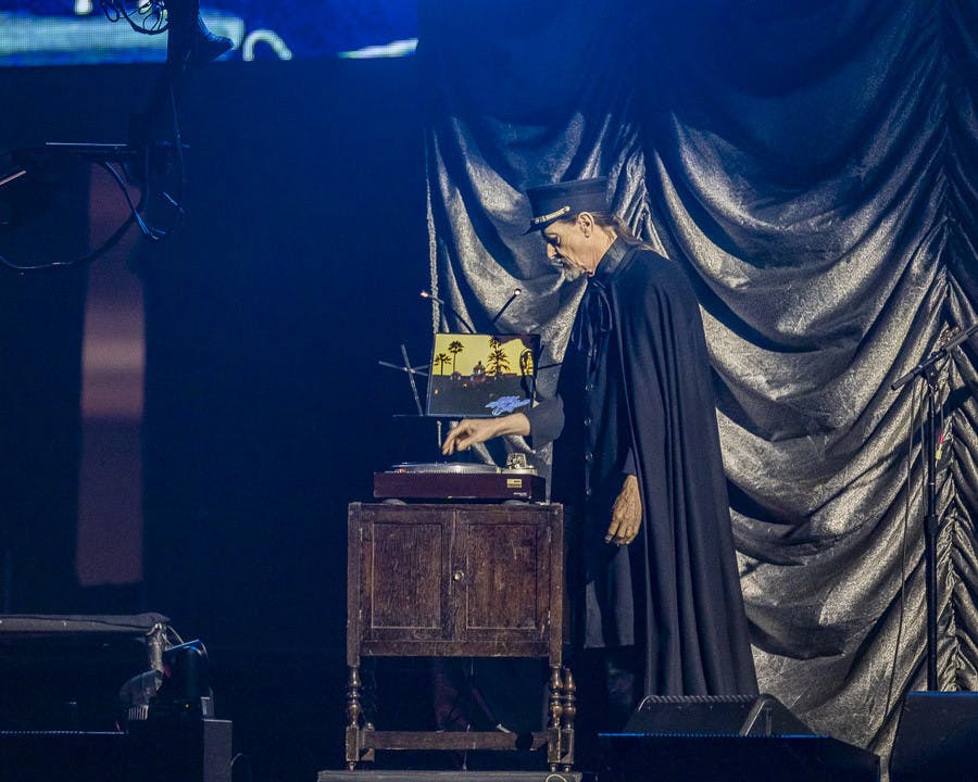 A cast member dressed in a cloak and bellhop costume places the "Hotel California" vinyl on a record player to kick off the Eagles concert on March 30, 2023, at Colonial Life Arena. The band opened up the show with its hit song, "Hotel California."