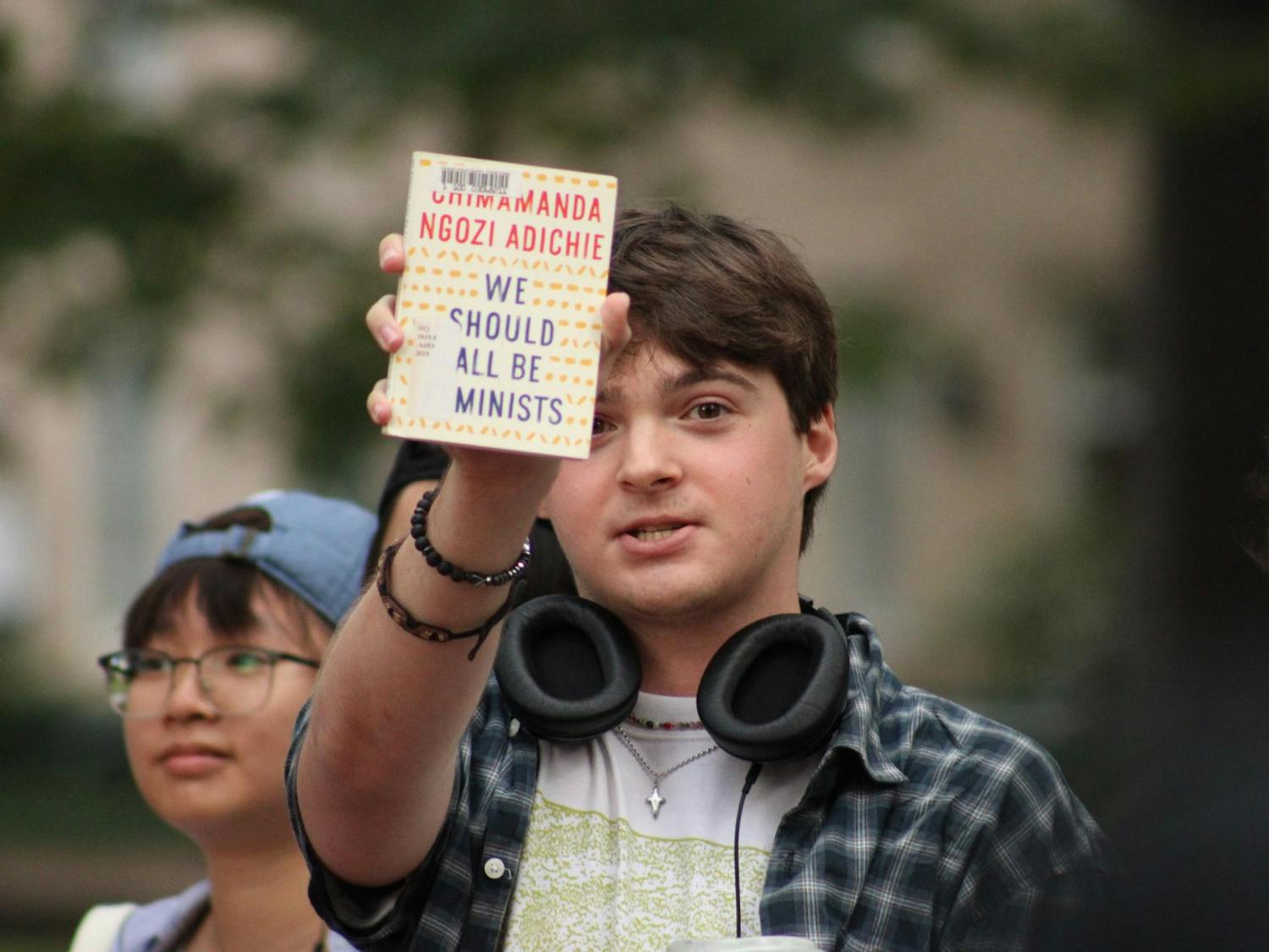 All the contestants in the Performative Male Contest bring various items with them to present to the audience. Here, a competitor displays a book with the title “We Should All Be Feminists”.