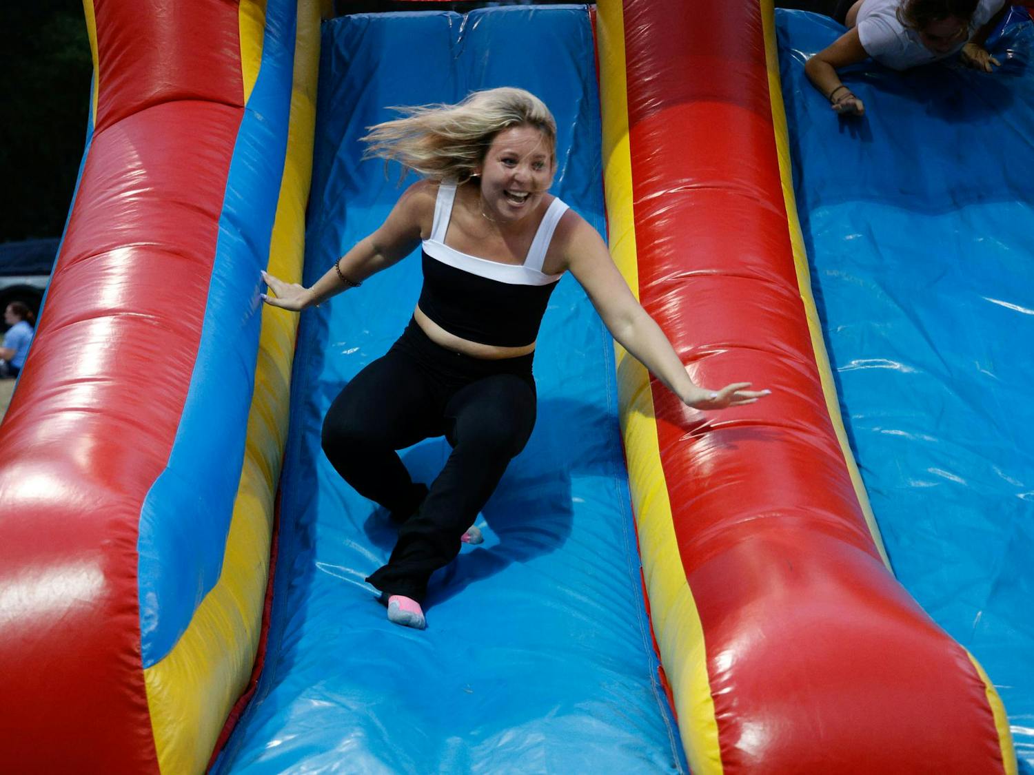 A student races down the slide in an inflatable obstacle course at Blatt Bonanza on Sept. 18, 2024, at Blatt Field. Racers entered through an opening at the other end of the obstacle course and made their way through the course before reaching the ending slide.