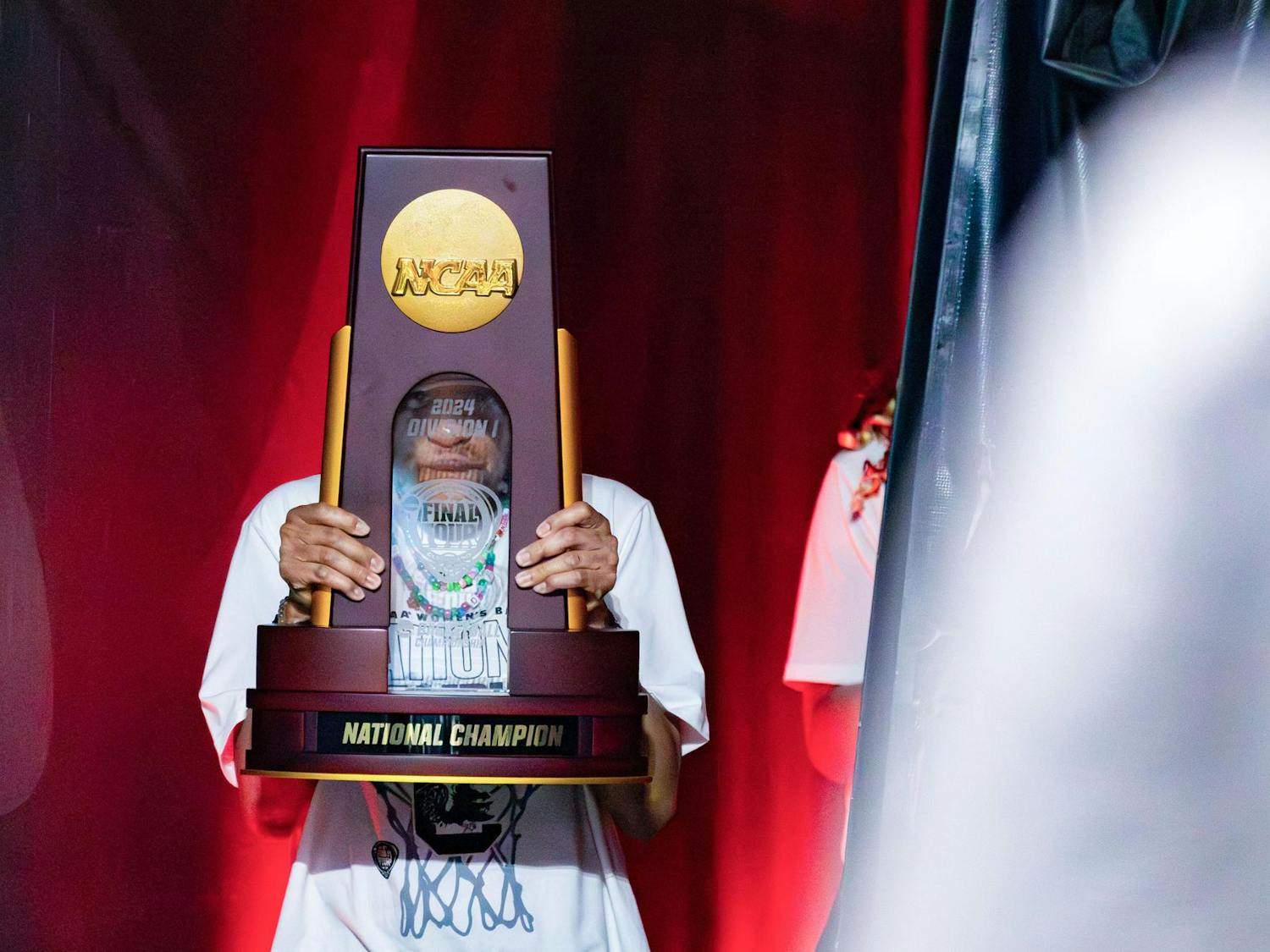 Head coach Dawn Staley peers through the center of the NCAA Women's National Championship trophy prior to the start of the welcome home celebration for the 2024 National Champion South Carolina Women's Basketball team at Colonial Life Arena on April 8, 2024. Staley is the first Black coach to win three NCAA Division 1 titles.