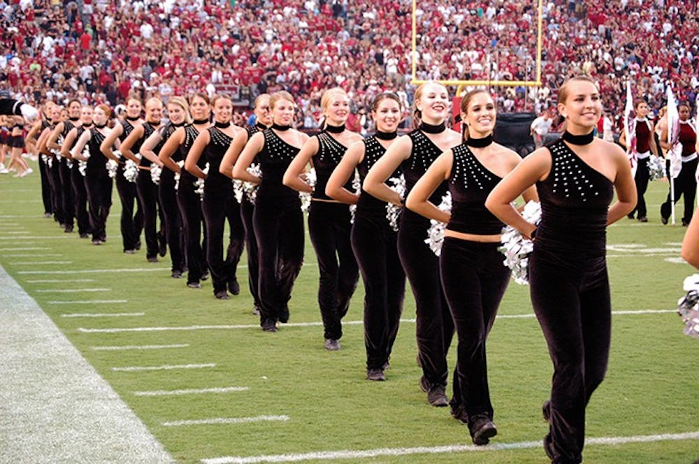 Members of the Carolina Coquettes dance team walk down the football field on game day.