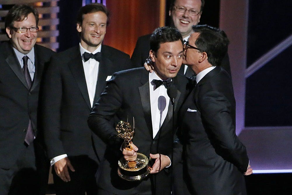 Stephen Colbert, right, whispers his acceptance speech into Jimmy Fallon's ear after winning Outstanding Variety Series for "The Colbert Report" during the 66th Annual Primetime Emmy Awards at Nokia Theatre at L.A. Live in Los Angeles on Aug. 25, 2014. (Robert Gauthier/Los Angeles Times/TNS)