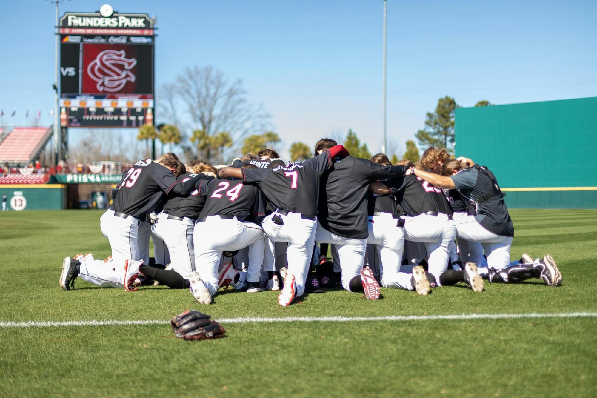 The Carolina baseball team takes a knee before their game against UNCG on Feb. 20, 2022. Carolina defeated UNCG in the last game of their series 8-7.