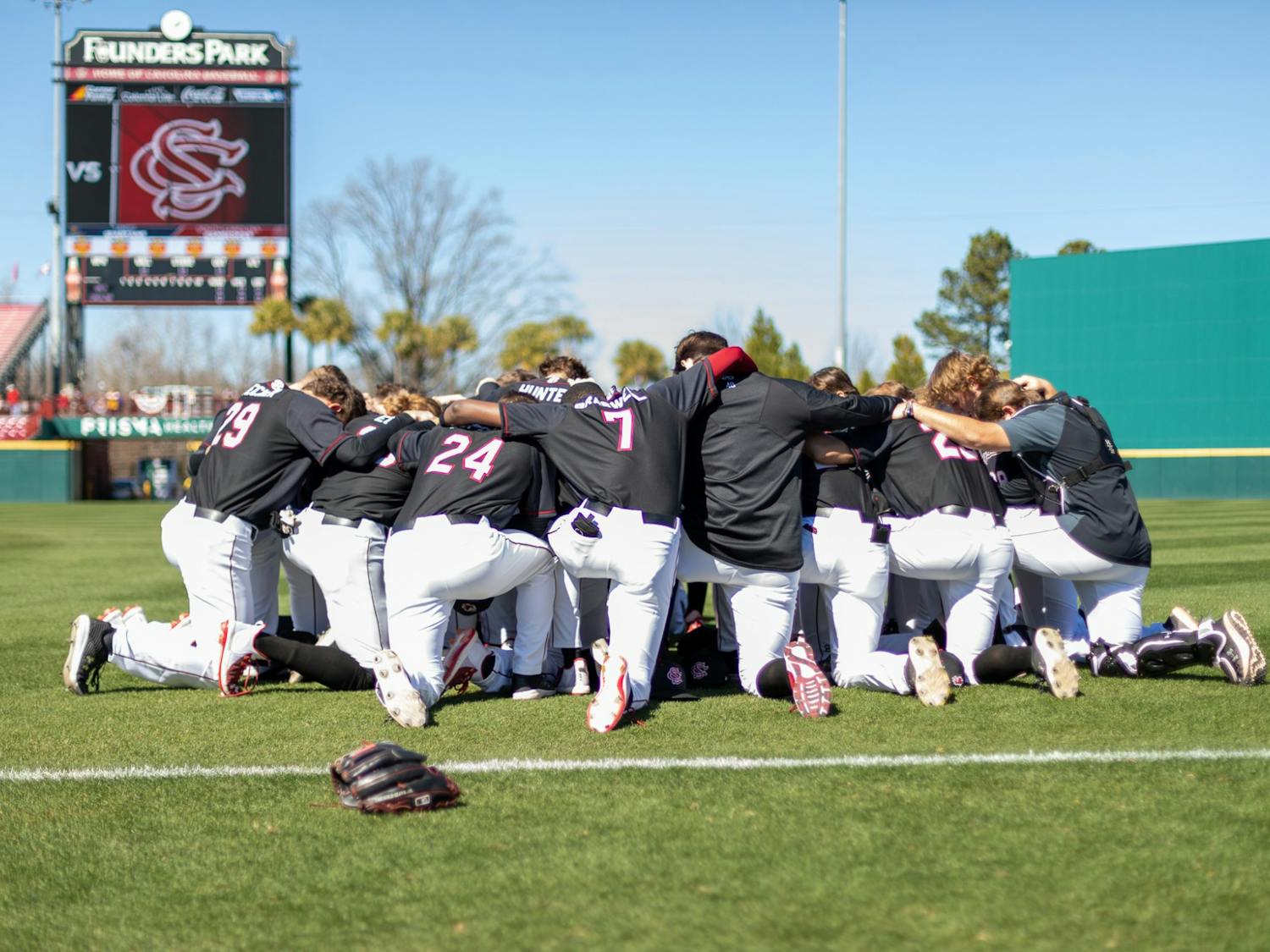 The Carolina baseball team takes a knee before their game against UNCG on Feb. 20, 2022. Carolina defeated UNCG in the last game of their series 8-7.