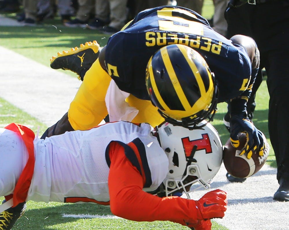 Michigan&apos;s Jabrill Peppers (5) is tackled by Illinois&apos; Stanley Green in the first quarter on Saturday, Oct. 22, 2016, at Michigan Stadium in Ann Arbor, Mich. The host Wolverines won, 41-8. (Kirthmon F. Dozier/Detroit Free Press/TNS)