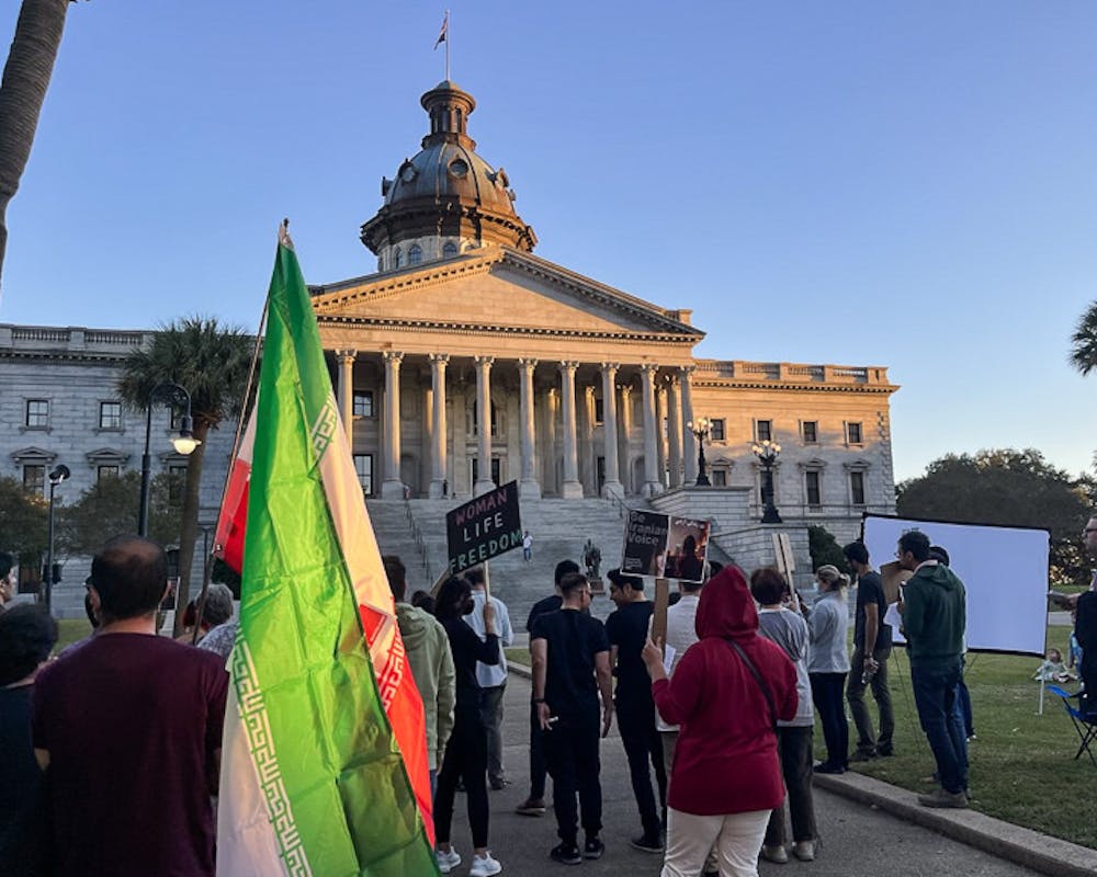 <p>Columbia residents gather in front of the statehouse with Iranian flags and protest signs on Oct. 4, 2022. The 鶹С򽴫ý Iranian Student Association held a protest at the statehouse to show solidarity with their country's women.</p>