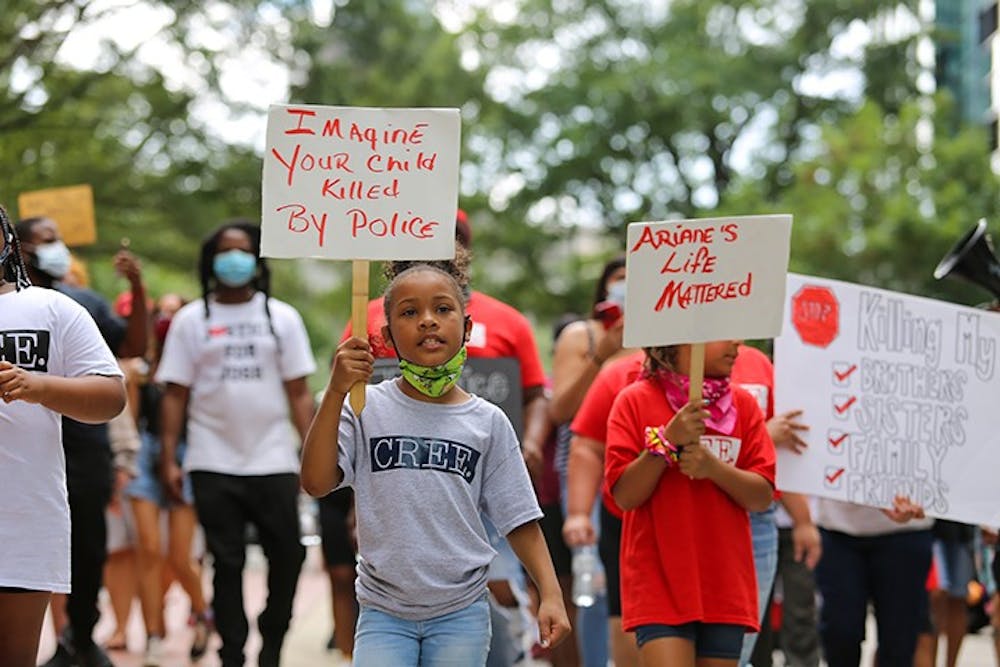 <p>A child leading the march holds a sign reading "Imagine your child killed by police." Children led the march from the Statehouse to the judicial center on Aug. 29.</p>
