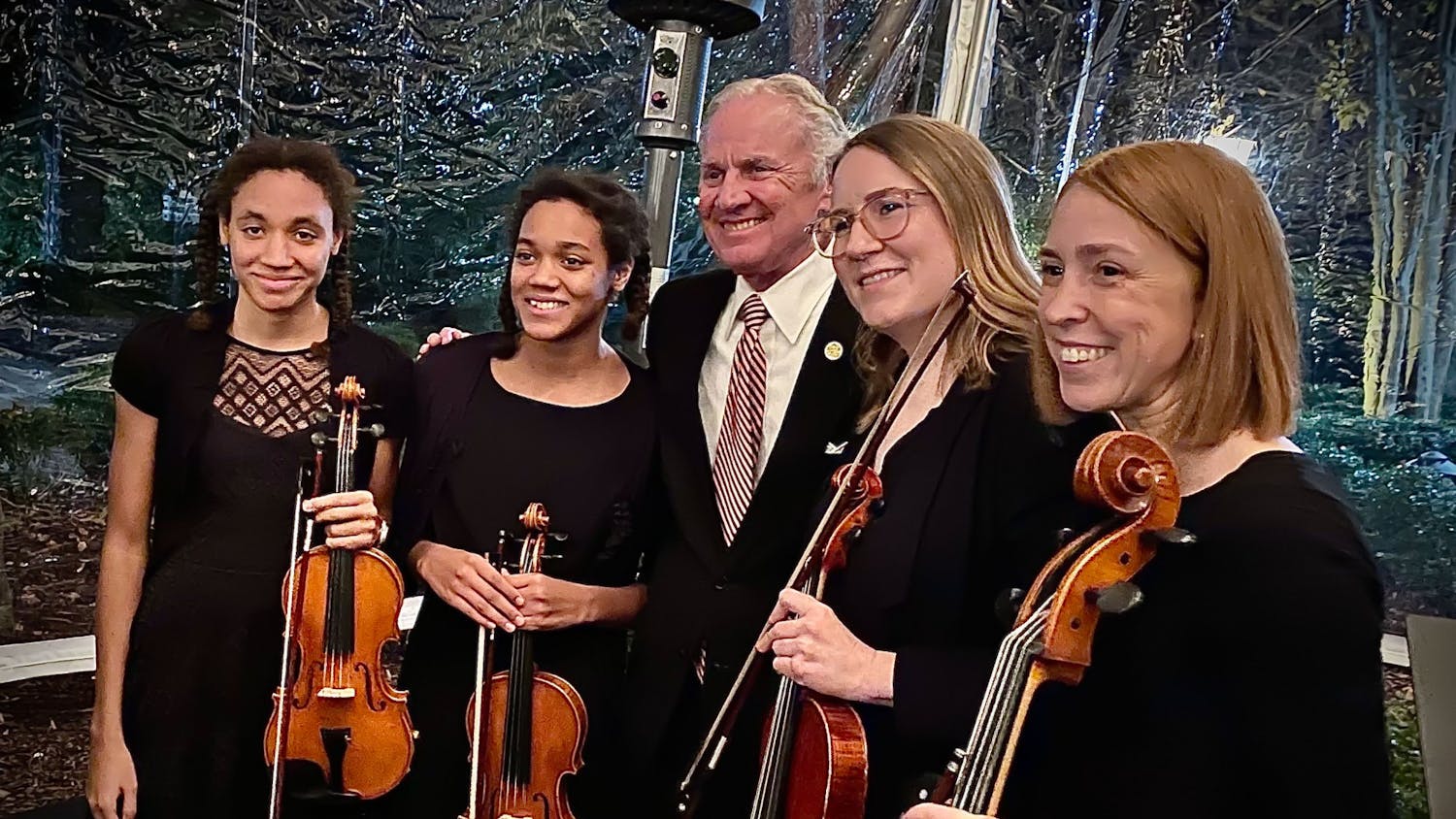 Two students at the Suzuki Academy of Columbia stand with Gov. Henry McMaster (center), violin instructor Kristen Harris (second from right) and academy director Sarah Evanovich (right) stand together at a SoundBites fundraising event in December 2021. SoundBites is a nonprofit based in South Carolina that is dedicated to providing high-quality instruments to those who cannot afford them.