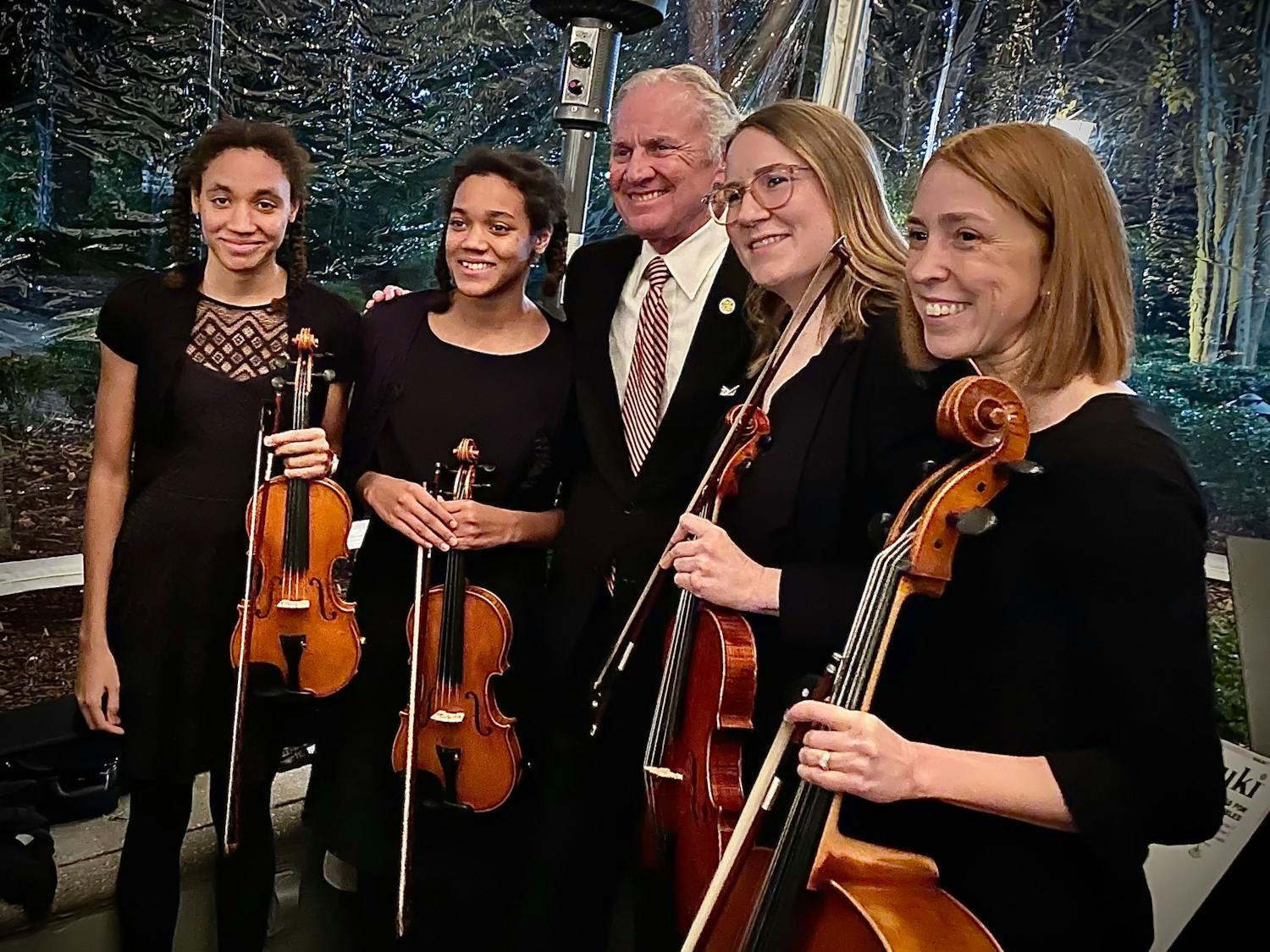 Two students at the Suzuki Academy of Columbia stand with Gov. Henry McMaster (center), violin instructor Kristen Harris (second from right) and academy director Sarah Evanovich (right) stand together at a SoundBites fundraising event in December 2021. SoundBites is a nonprofit based in South Carolina that is dedicated to providing high-quality instruments to those who cannot afford them.