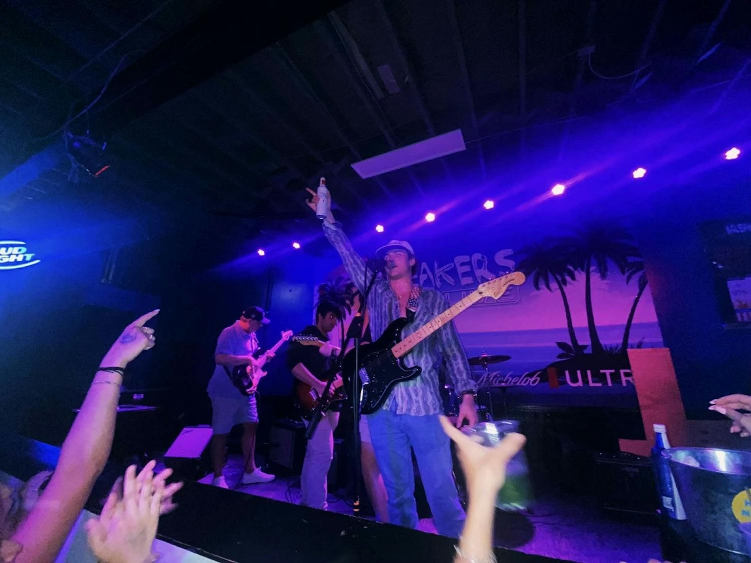 Lead vocalist Jack Brecher raises his drink to a crowd as the band prepares for its next song at Breaker’s Live in Five Points on March 26, 2023. The group has been performing live at venues since February 2023.&nbsp;