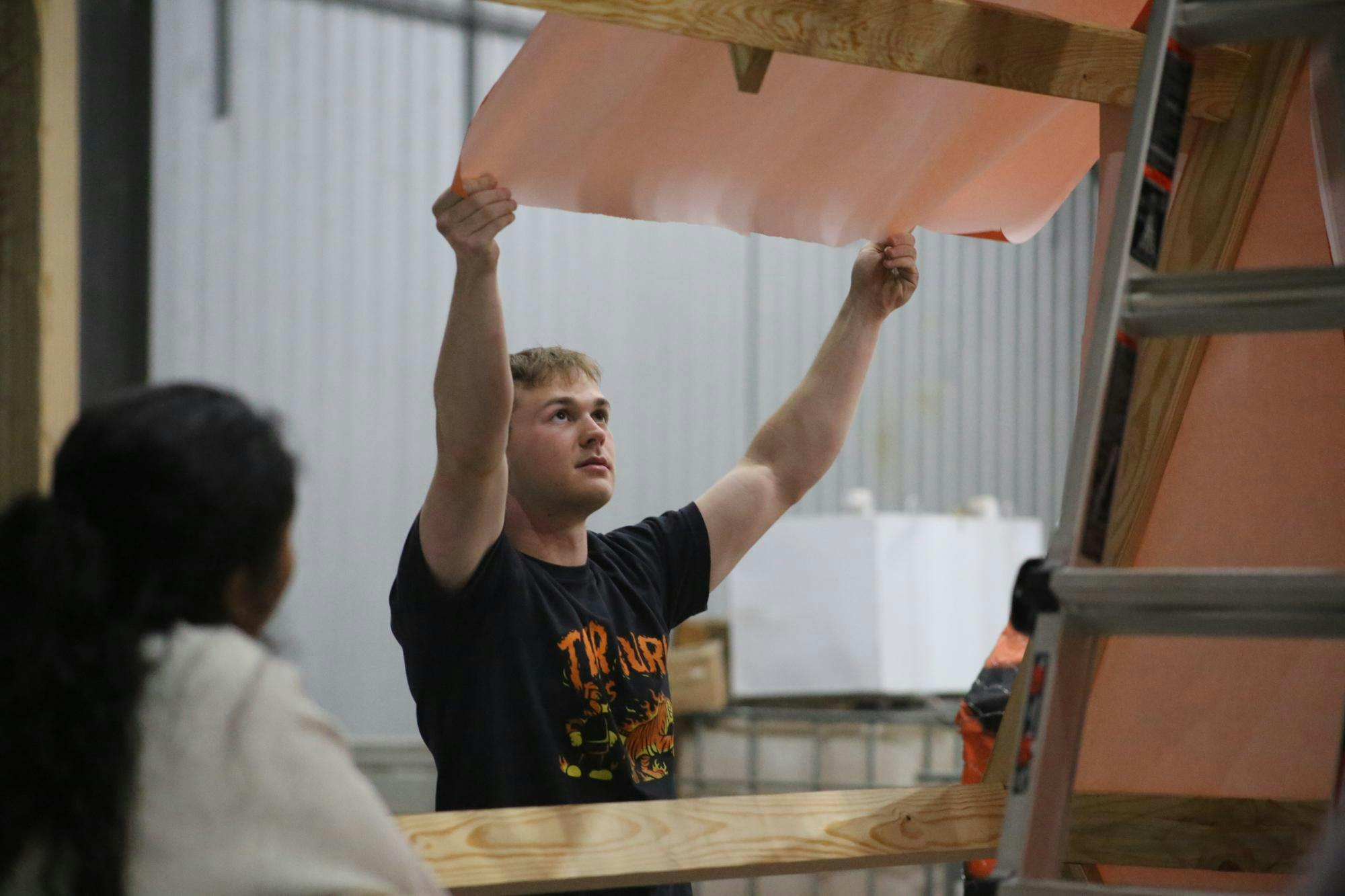 Second-year biomedical engineering student Connor Prince raises the orange paper up to measure on Nov. 12, 2025, at the biomass facility. Members of the American Society of Mechanical Engineers met daily from Nov. 10 to 14 and Nov. 17 to 19 to plan and build the tiger structure.