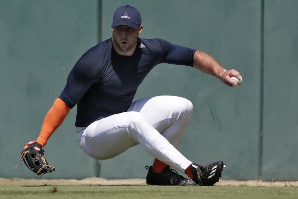 Former NFL quarterback Tim Tebow loses his footing as he fields a ball during outfield drills at USC's Dedeaux Field in Los Angeles during a private baseball tryout on Tuesday, Aug. 30, 2016. (Robert Gauthier/Los Angeles Times/TNS)