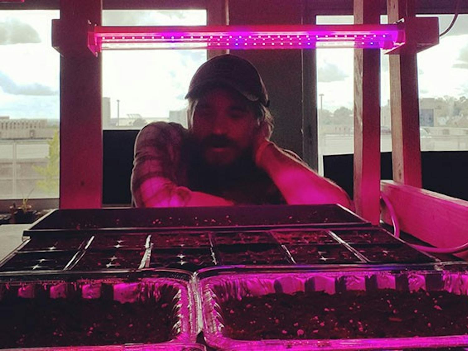 In his home, graduate student Pete Tereszkiewicz observes seeds he planted as part of his research.