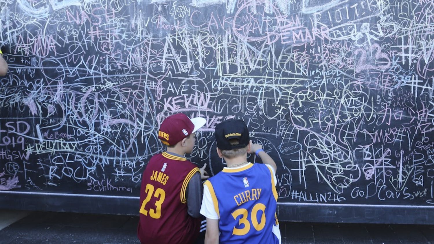 Young fans of LeBron James and Stephen Curry fan sign a chalk wall, sponsored by Rustoleum, outside Quicken Loans Arena before the Cleveland Cavaliers play host to the Golden State Warriors in Game 3 of the NBA Finals on Wednesday, June 8, 2016, in Cleveland. (Phil Masturzo/Akron Beacon Journal/TNS)