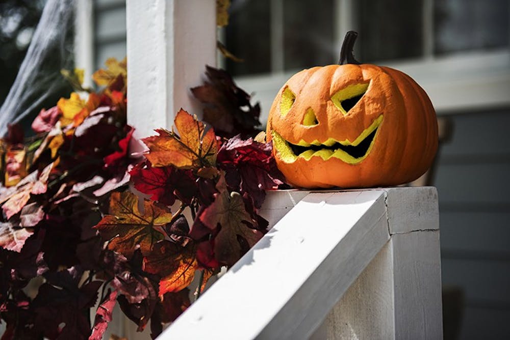 <p>A jack-o'-lantern sits on top of a railing. Carving pumpkins into jack-o'-lanterns is often a popular fall activity.</p>