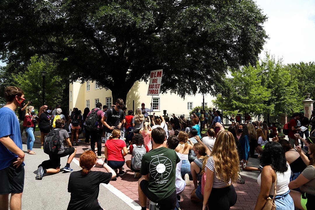 Most of the crowd surrounding Jim Gilles takes a knee while raising their first, the symbol of the Black Lives Matter movement, as a way to protest Jim Gilles and his anit-BLM sign.