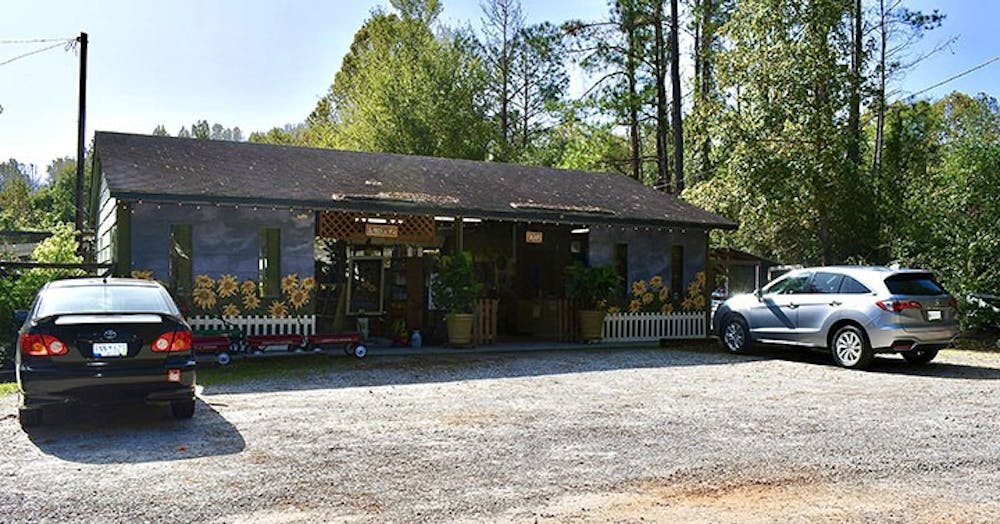 The front of Mill Creek Greenhouses. Walking through this building filled with plant pots will lead to different greenhouses and tentlike setups, where you can look at a variety of plants.