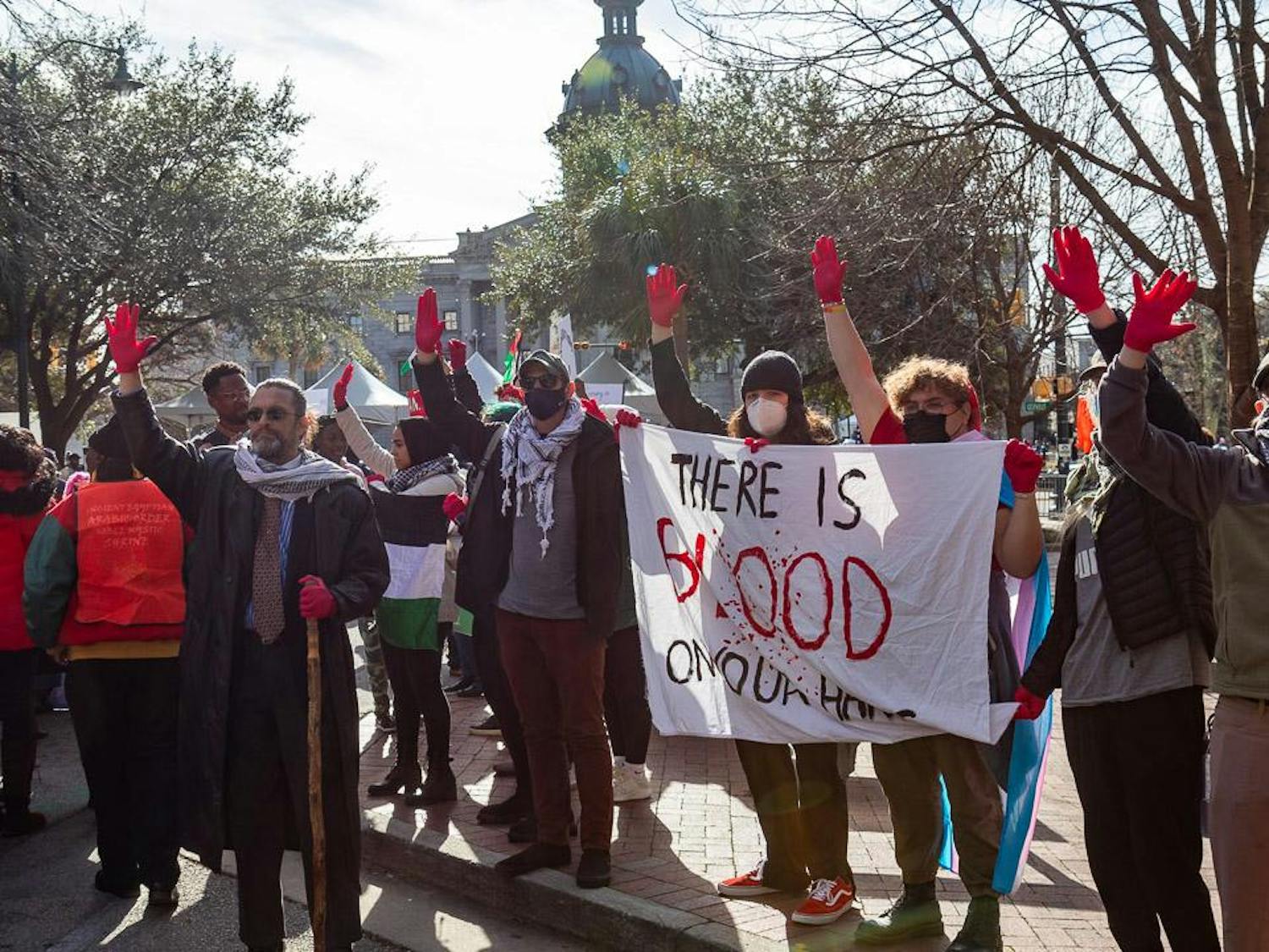 Protestors hold up painted gloves and a banner reading “There is blood on our hands” protesting for the end of the Israel-Palestine War outside of the South Carolina Statehouse on Jan. 15, 2024. Several groups including the Carolina Peace Contingent took part in the civil rights march to call for an end to the conflict.