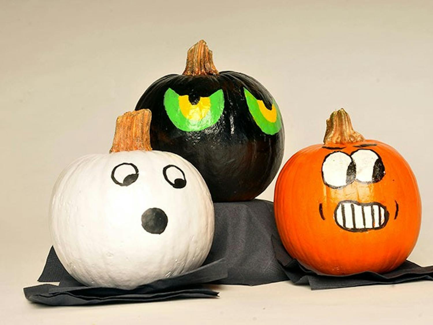 A set of three painted pumpkins on display. Painting a pumpkin is sometimes used as an alternative to carving it.