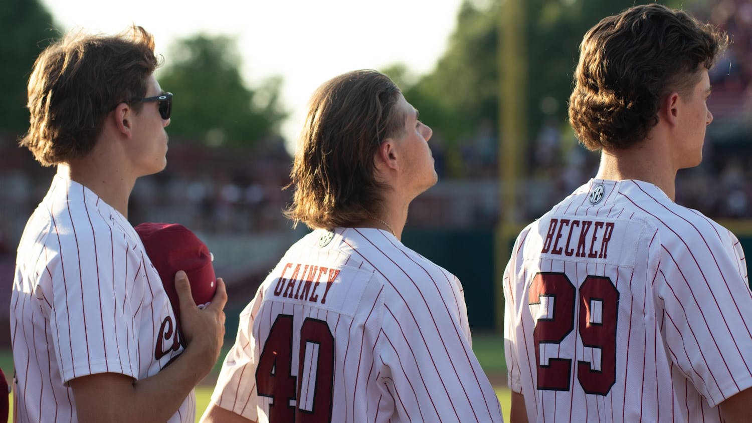Senior pitcher Garrett Gainey stands alongside junior pitchers Tyler Dean and Matthew Becker during the National Anthem on April 19, 2024, at Founders Park. The South Carolina pitching staff collectively earned 11 strikeouts against the Arkansas Razorbacks.