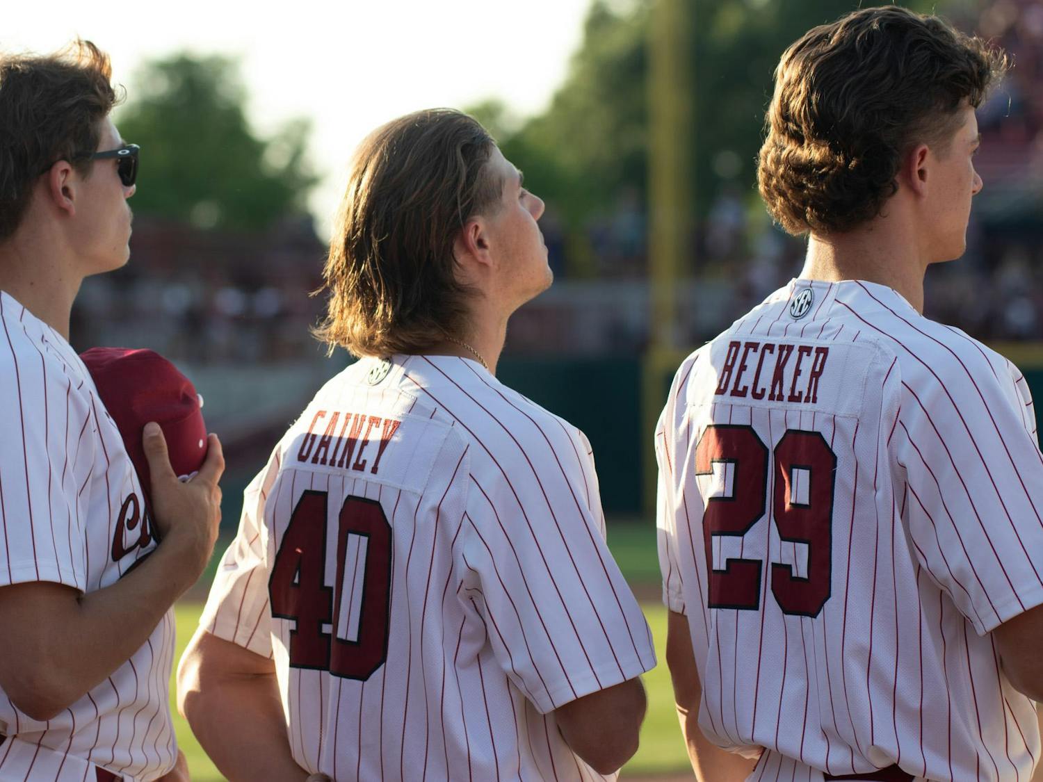 Senior pitcher Garrett Gainey stands alongside junior pitchers Tyler Dean and Matthew Becker during the National Anthem on April 19, 2024, at Founders Park. The South Carolina pitching staff collectively earned 11 strikeouts against the Arkansas Razorbacks.