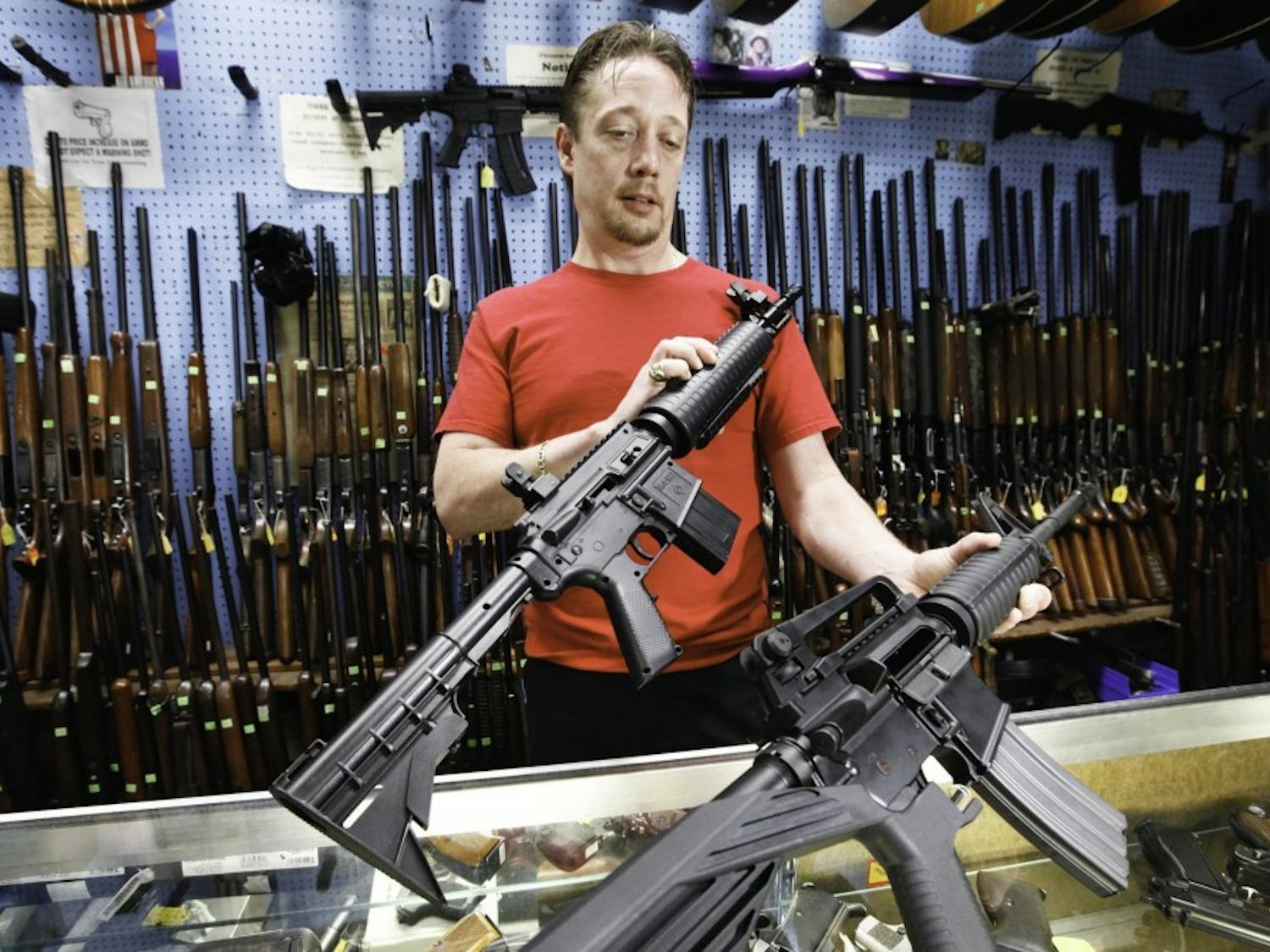Shawn Bertke, manager of Rich's Pawn Shop in Dayton, Ohio, has two guns for sale that look virtually alike. At left is a $45 Crosman BB gun; the other is a $1,200 real AR-15 rifle. (Chris Stewart/Dayton Daily News/MCT)