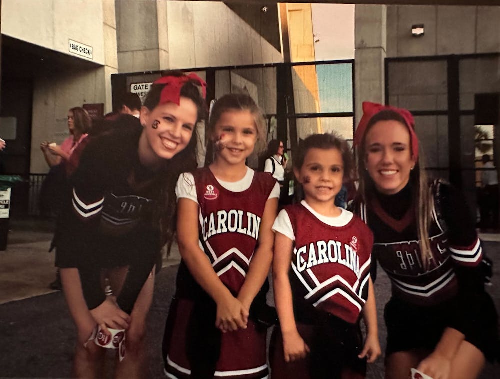 <p>Camila and Sophia Burnett pose next to Gamecock cheerleaders in their own cheerleading outfits. Growing up as Gamecock fans in Hilton Head, S.C., the sisters said attending games was not an uncommon occurrence for their family.</p>