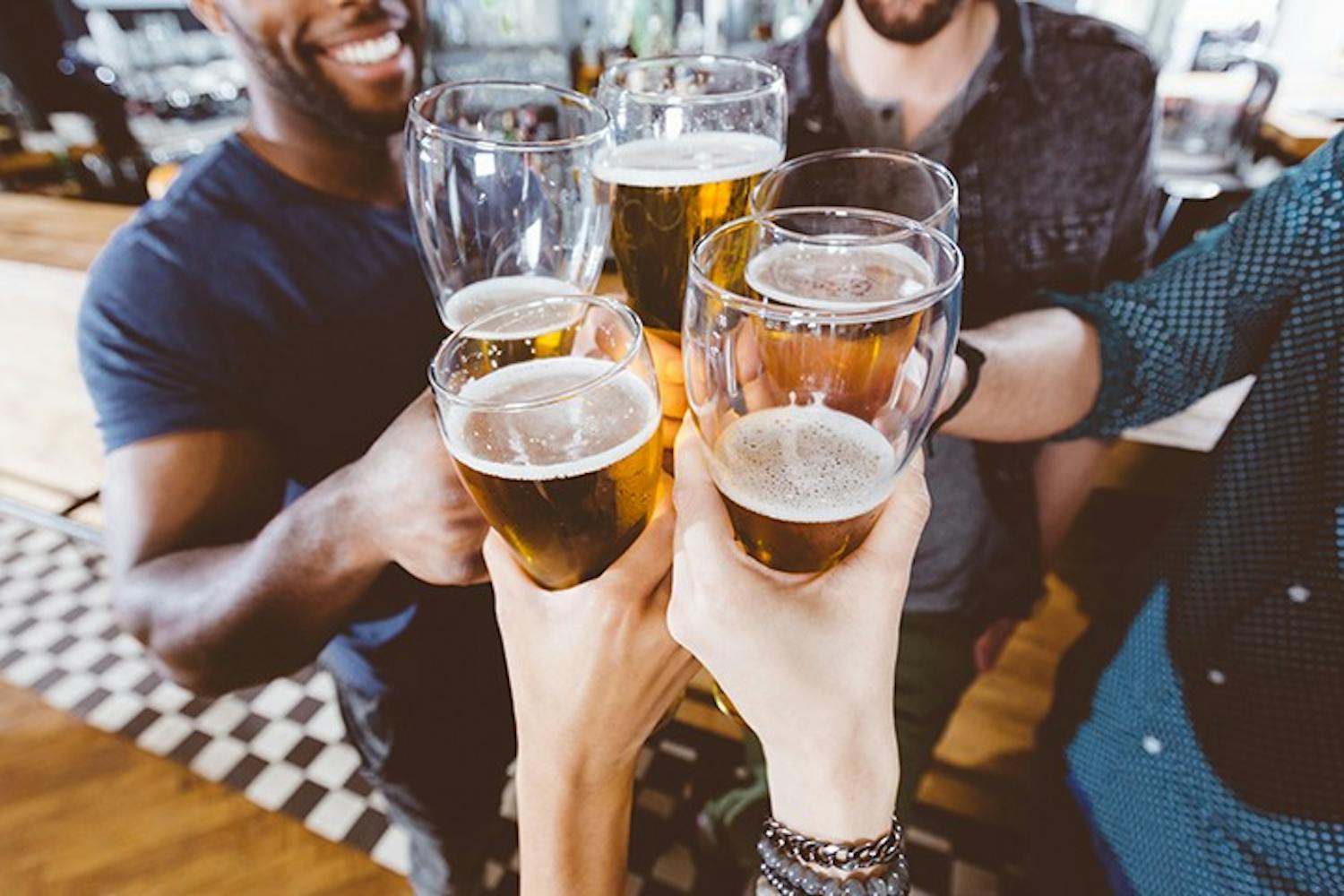  A group of people clink their glasses of beer together.
